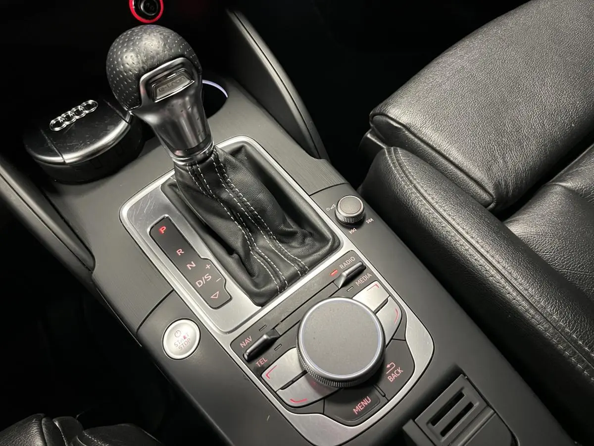 Gros plan sur la console centrale noire en cuir et aluminium de l'Audi A3 1.4 TFSI e-tron S line avec levier de vitesses automatique et commandes MMI.