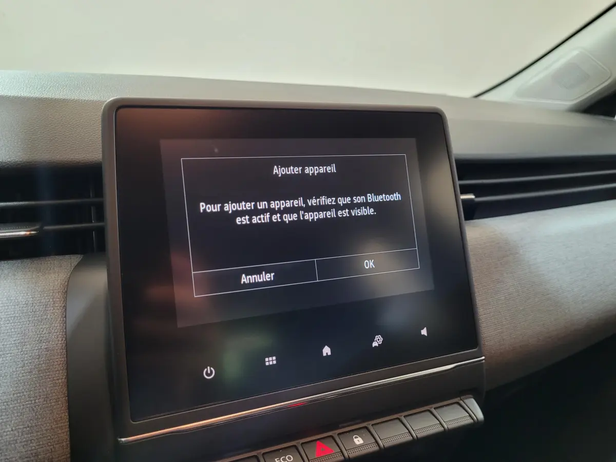 Écran tactile central affichant l'ajout d'appareil Bluetooth dans l'habitacle gris clair d'une Renault Clio 2025.