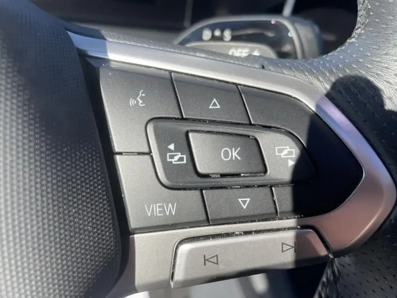 Gros plan sur les commandes au volant du Volkswagen Tiguan 1.5 eHybrid gris métal, boutons multifonctions avec finition R-line.
