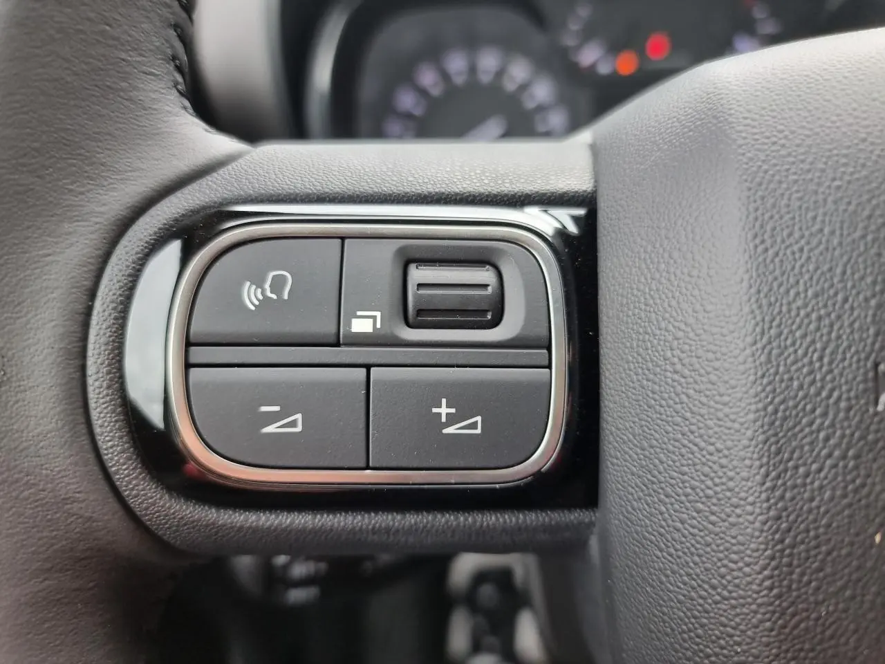 Gros plan sur les commandes de volume et téléphone au volant du Citroën C3 Aircross, intérieur noir.