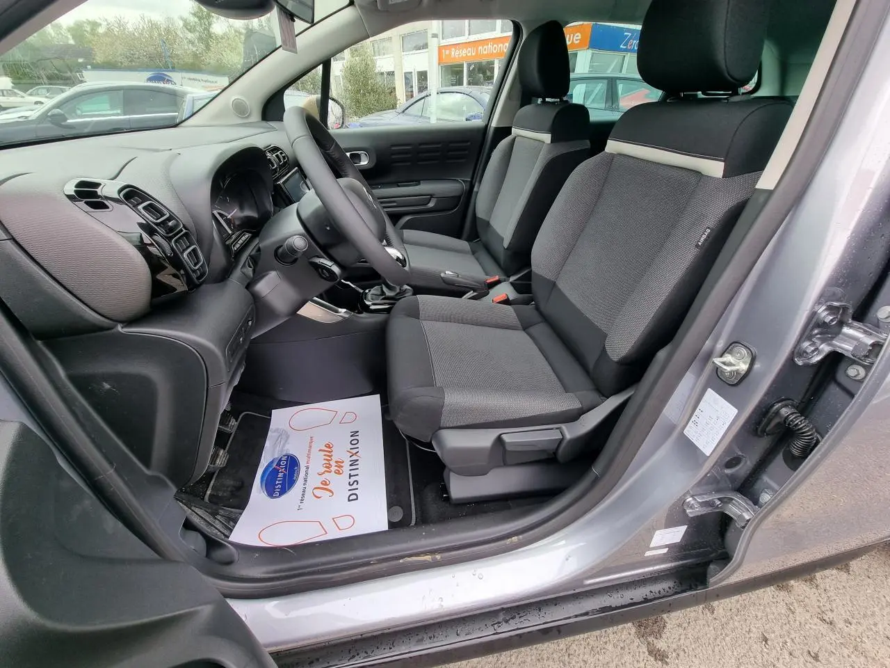 Vue intérieure côté conducteur de la Citroën C3 Aircross gris Artence, sièges tissu noir et tableau de bord moderne.