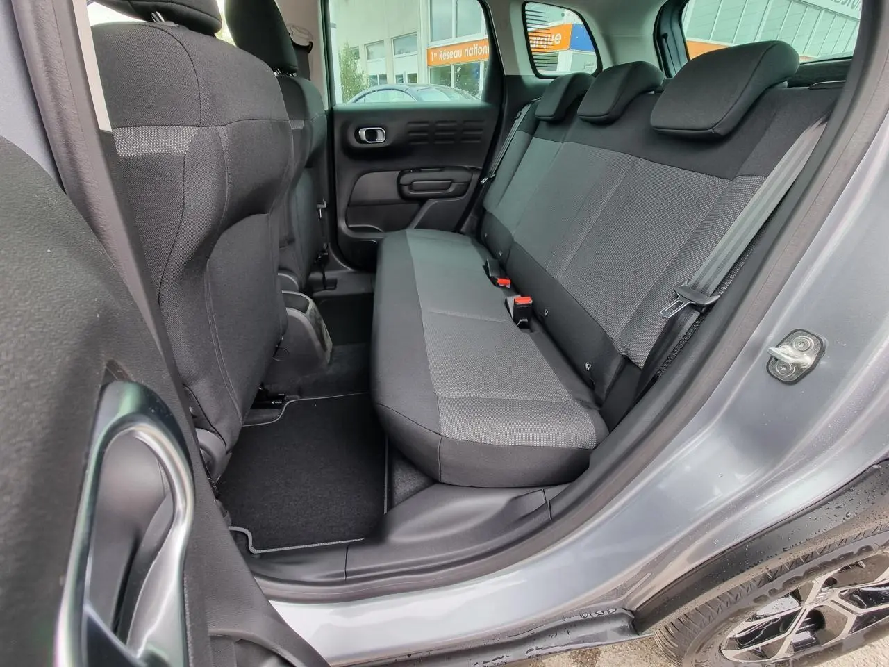 Vue intérieure côté arrière droit du Citroën C3 Aircross gris Artence, montrant la banquette arrière en tissu gris.