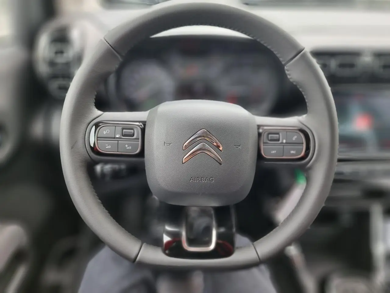 Vue rapprochée du volant noir du Citroën C3 Aircross 2022 avec commandes intégrées et logo chromé central.