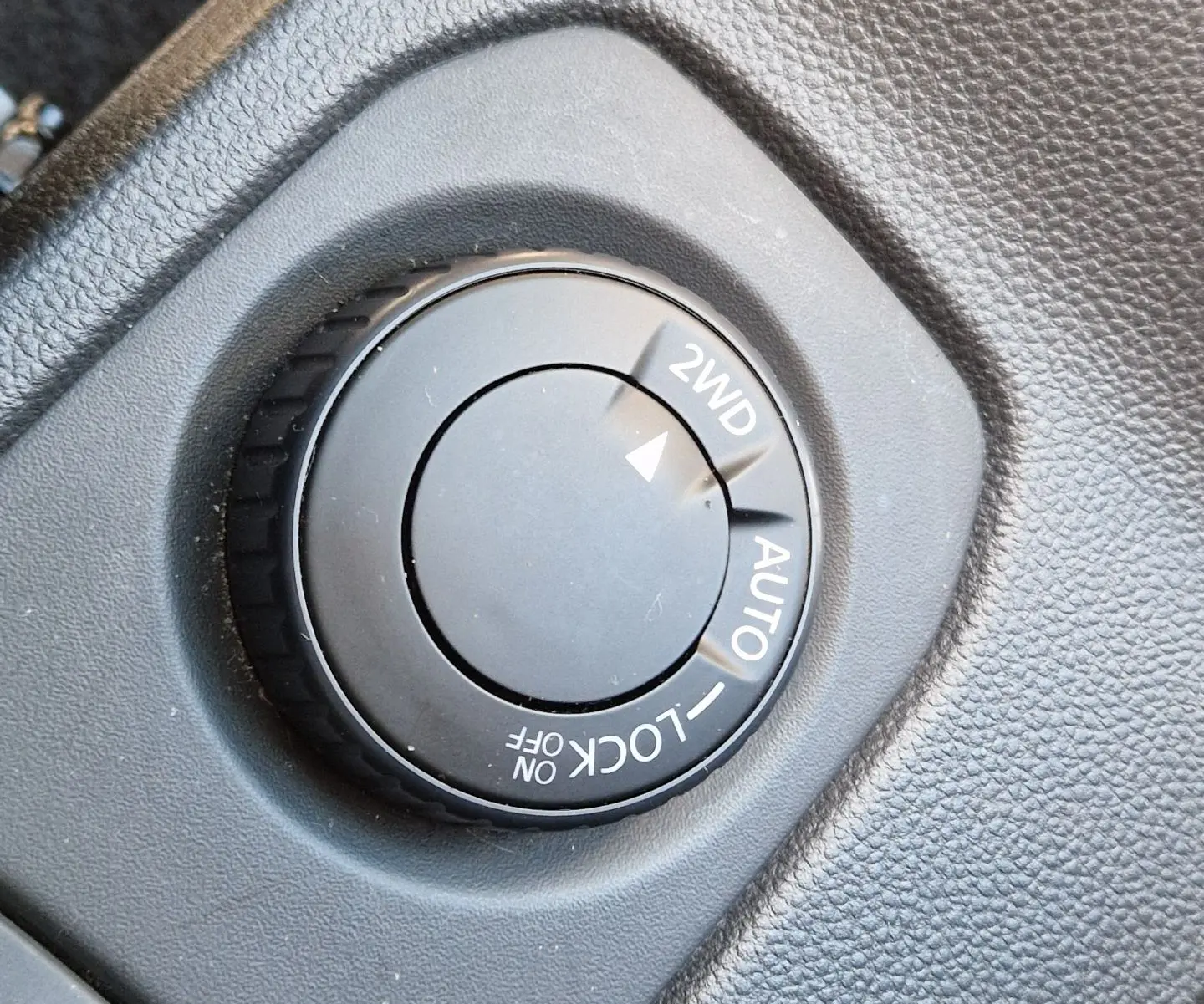 Gros plan sur le sélecteur de mode 4x4 dans l'habitacle du Dacia Duster blanc 2024, version Expression+ avec jantes alu 17 pouces.