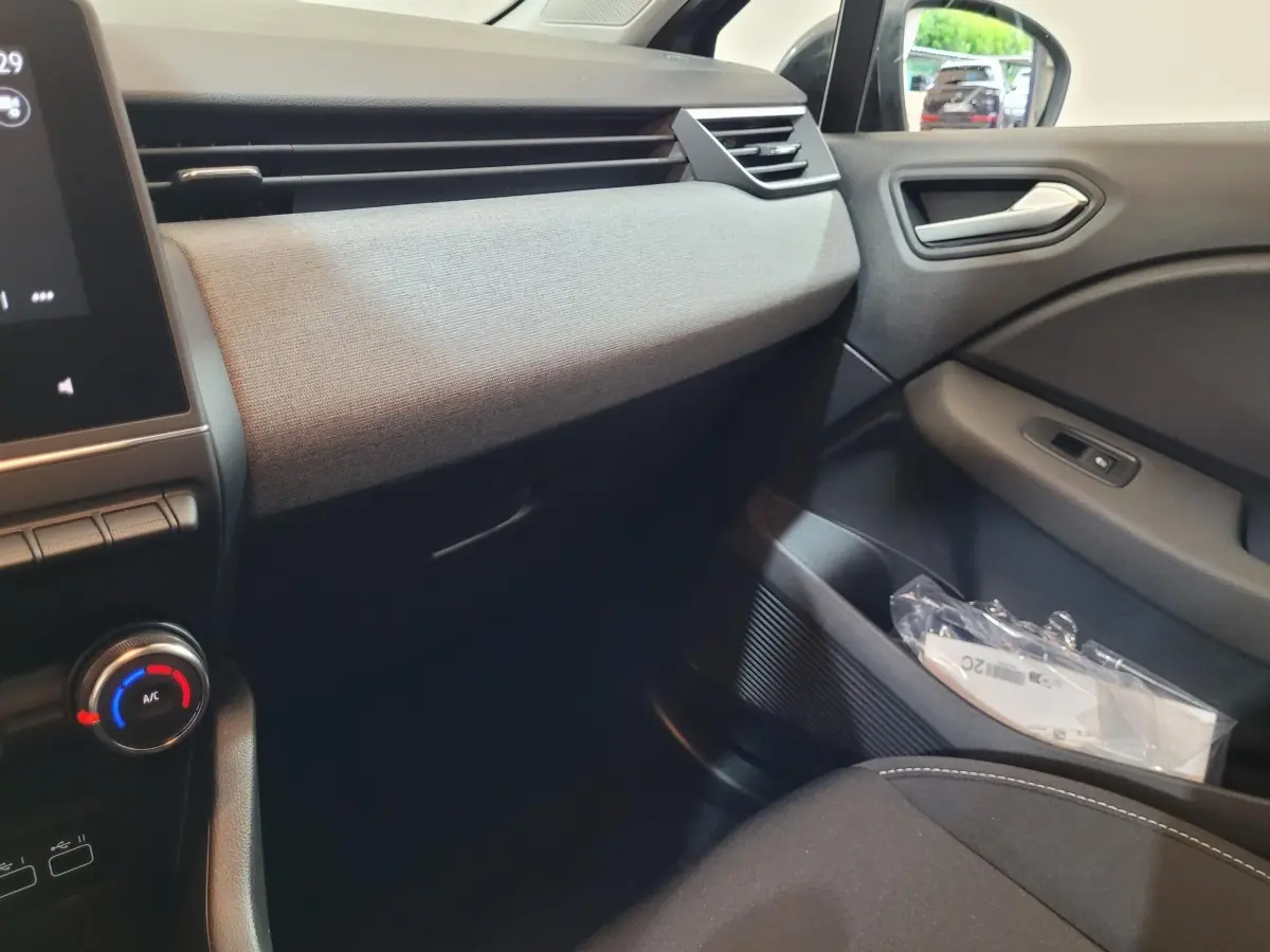 Intérieur avant droit de la Renault Clio gris foncé 2025, tableau de bord avec écran tactile et commandes climatisation visibles.