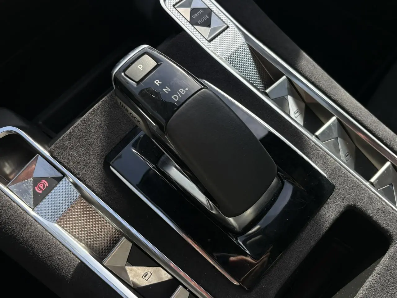 Gros plan sur la console centrale noire du DS7 1.6 E-Tense 225, avec levier de vitesses et commandes en aluminium.
