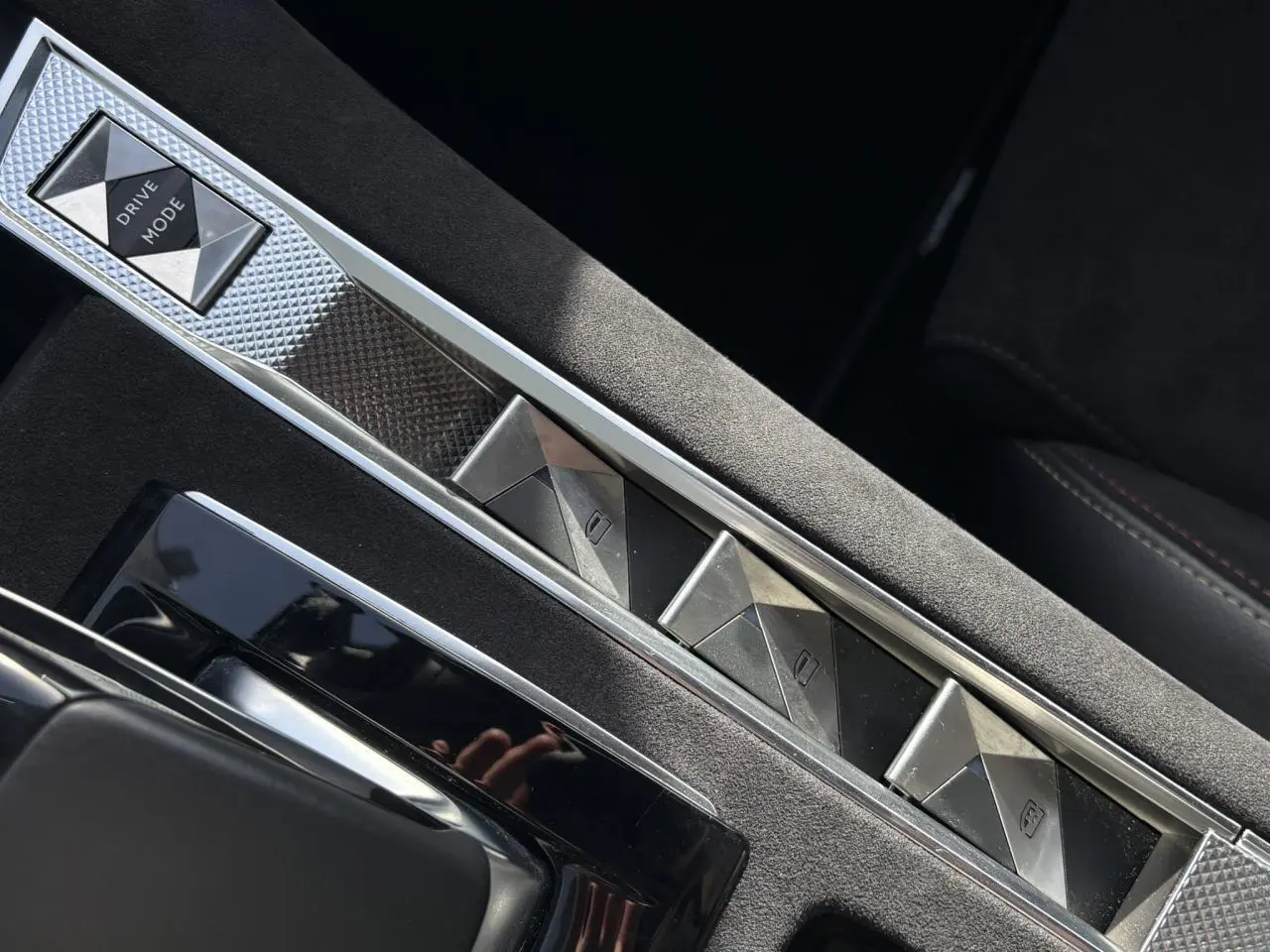 Gros plan sur la console centrale en Alcantara noir profond avec boutons de commande à motifs géométriques du DS7 1.6 E-Tense 2024.