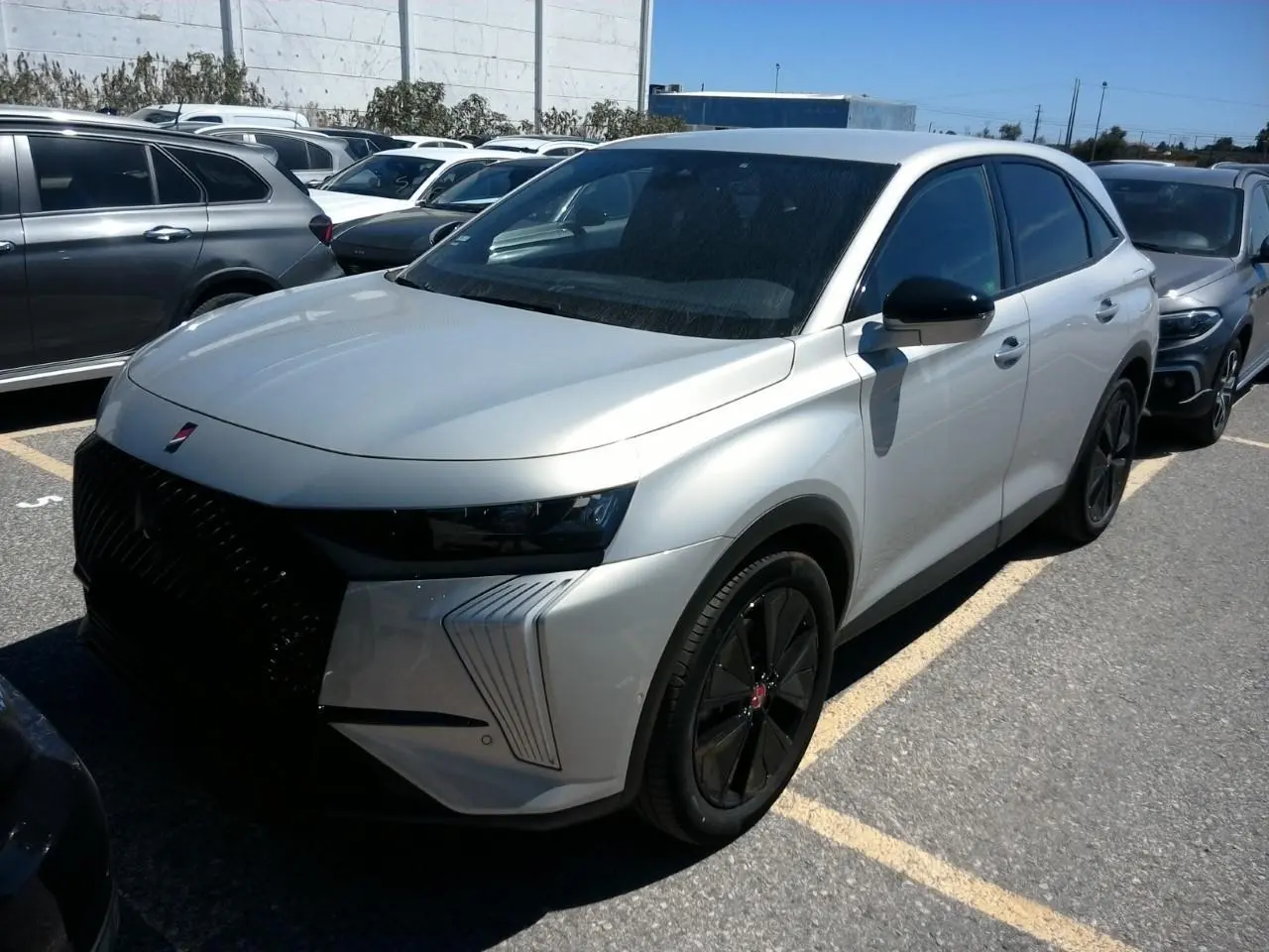 DS7 1.6 E-Tense 2024 en cristal pearl, vue 3/4 avant droit avec jantes noires et calandre marquée noire.