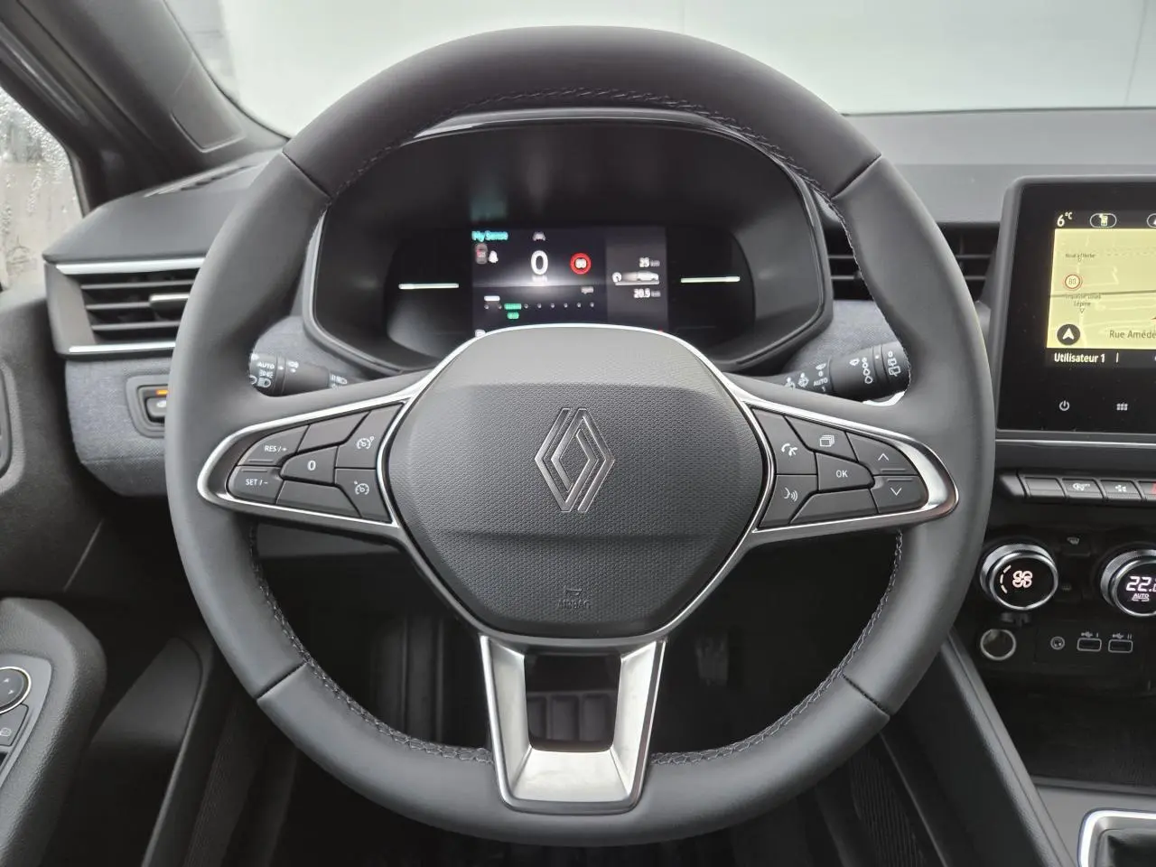 Vue rapprochée du volant multifonction noir et du tableau de bord numérique de la Renault Clio V gris schiste.