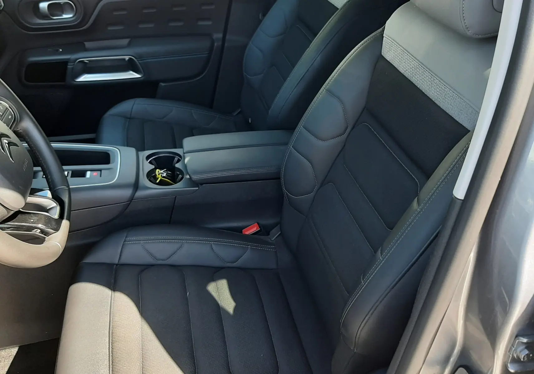 Vue intérieure côté conducteur du Citroën C5 Aircross Hybrid 2024 avec sièges en cuir noir et tissu gris, console centrale et porte gris acier.