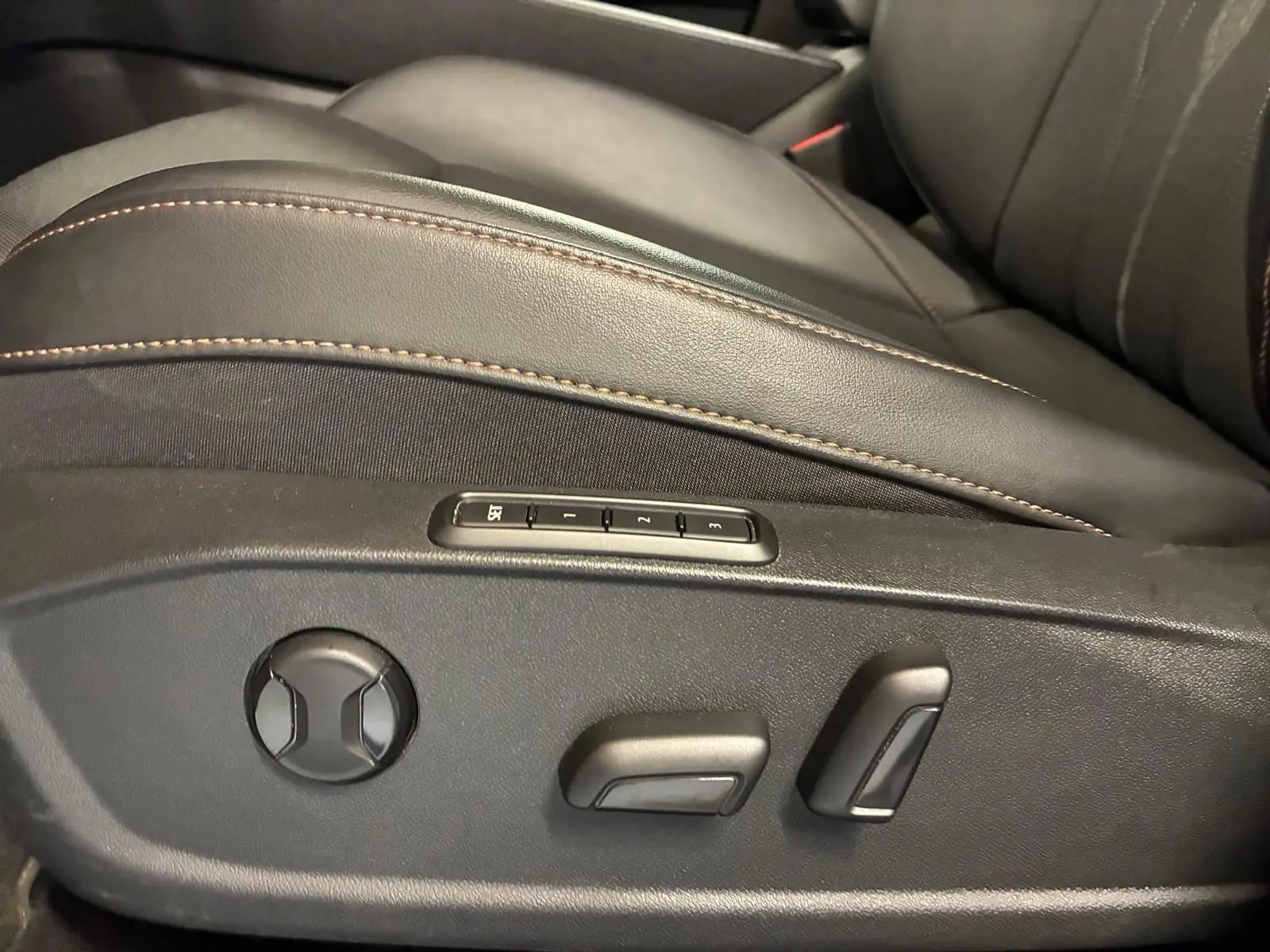 Gros plan sur les commandes électriques et mémoire du siège avant en cuir noir avec surpiqûres marron du CUPRA Formentor 2024.