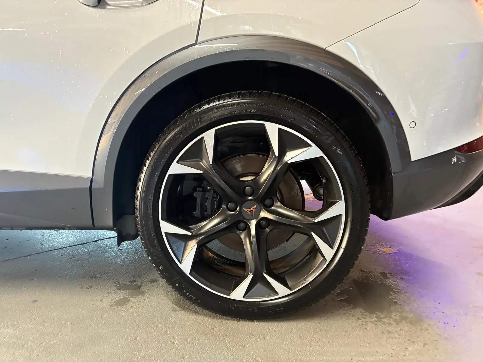 Gros plan sur la roue arrière droite d’un CUPRA Formentor gris 2024, mettant en valeur la jante alliage noire et argentée au design sportif.