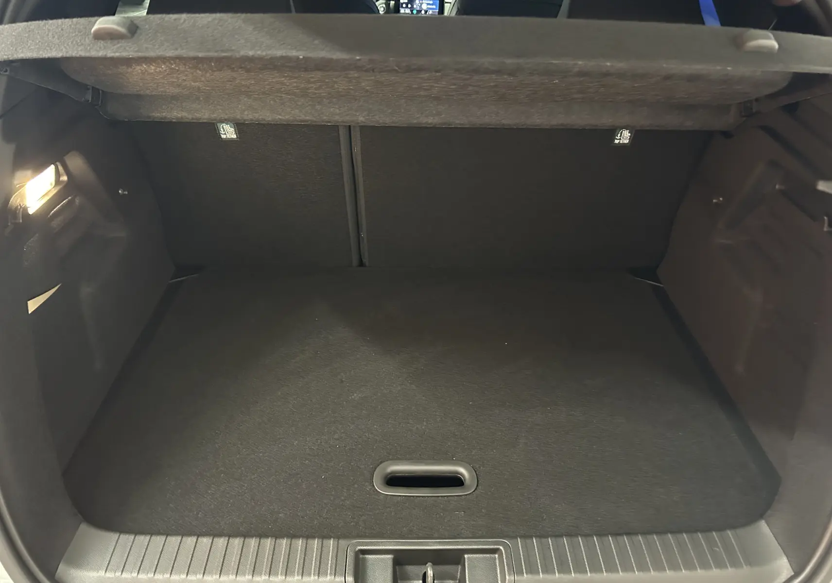Coffre ouvert du Renault Captur blanc nacré, vue intérieure montrant l'espace de chargement vide et la tablette arrière.