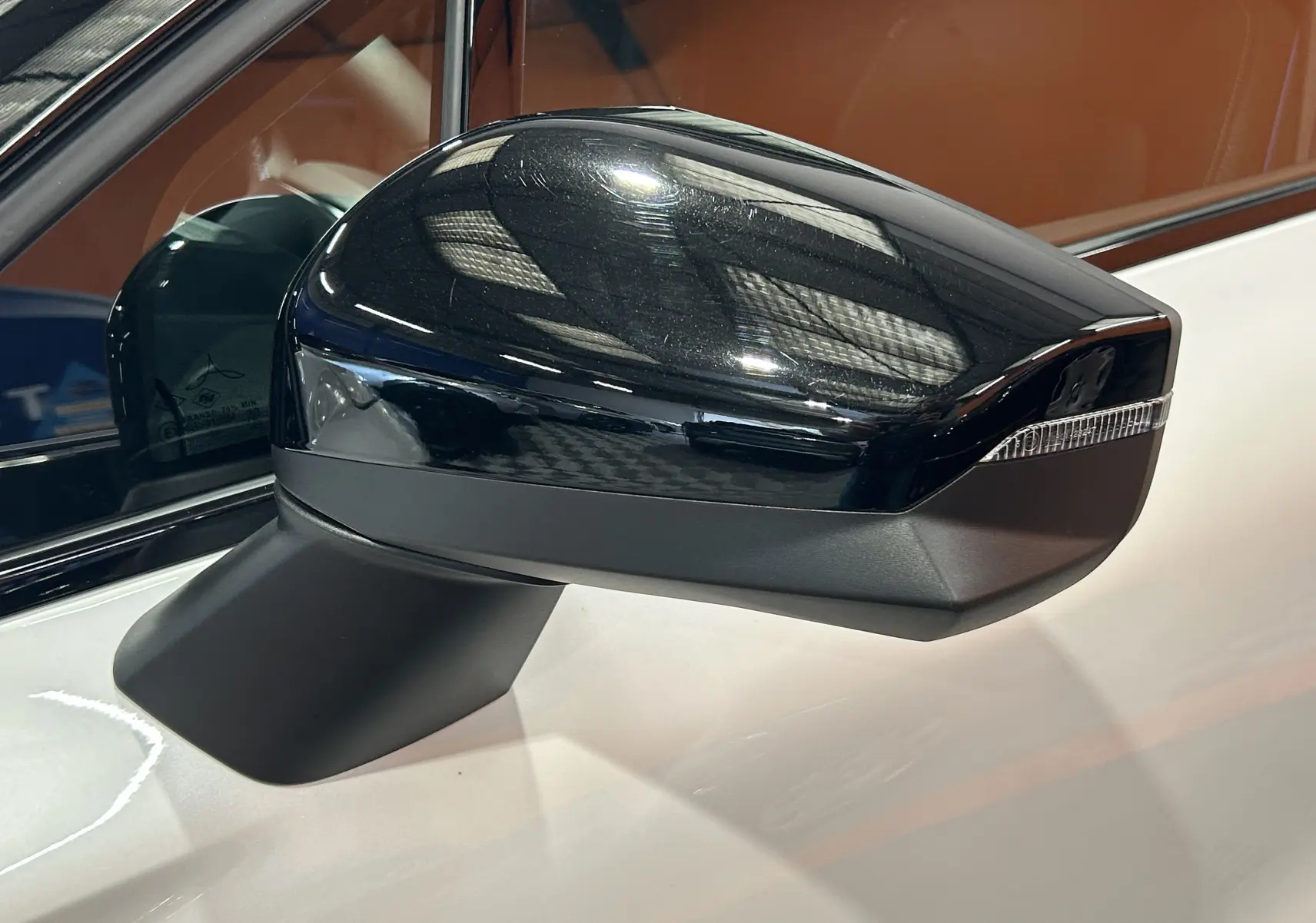 Gros plan sur le rétroviseur droit noir brillant du Renault Captur blanc nacré, avec clignotant intégré.