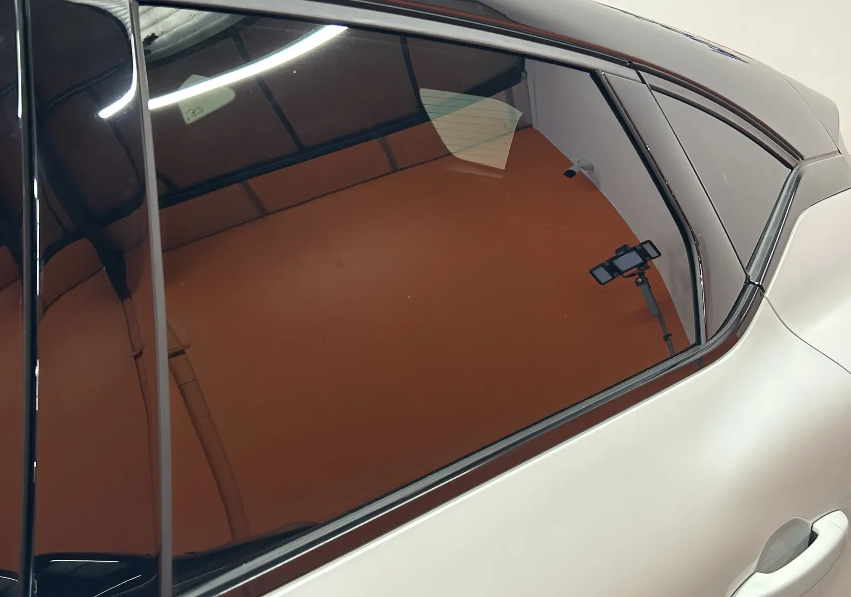 Vue rapprochée du côté droit arrière du Renault Captur blanc nacré avec vitrage teinté et poignée de porte visible.
