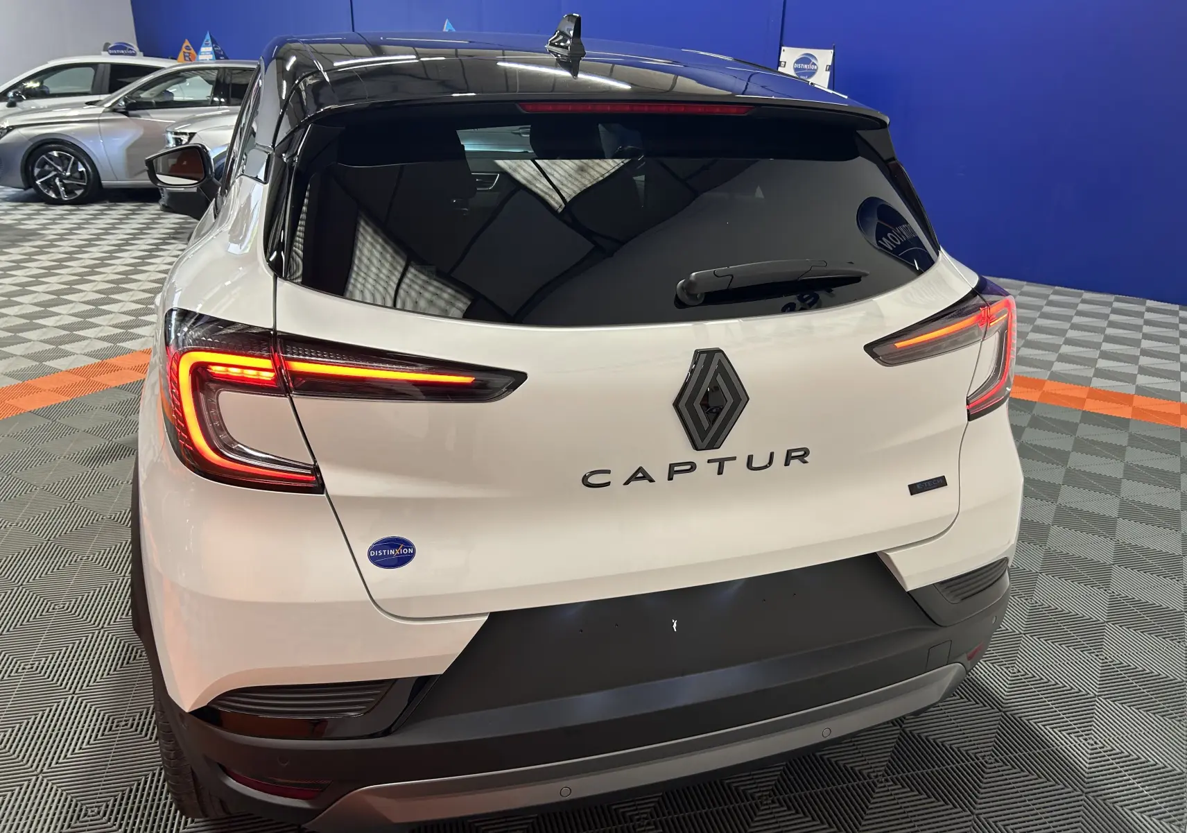 Vue arrière du Renault Captur blanc nacré avec feux LED allumés et toit noir dans un showroom.