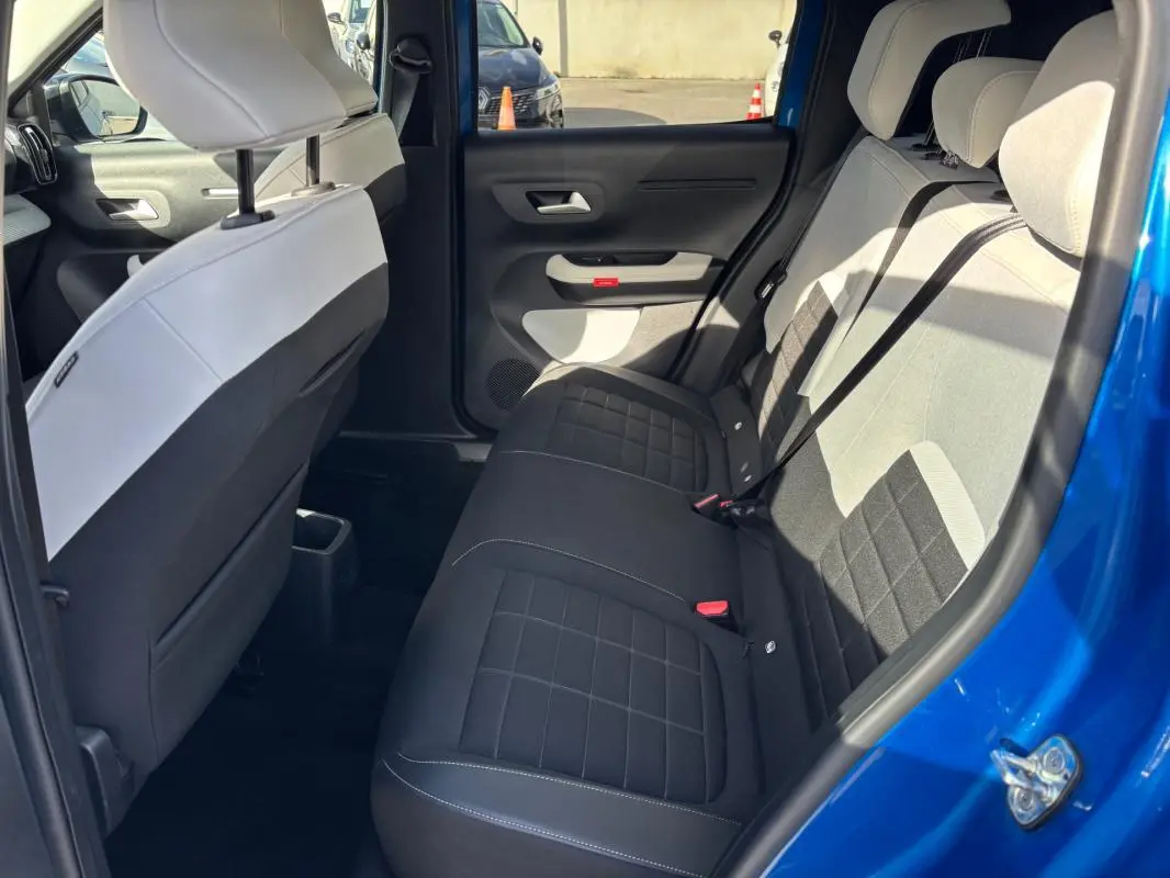 Vue intérieure côté arrière droit de la Citroën C3 bleu 2025, montrant les sièges arrière en tissu bicolore noir et gris.
