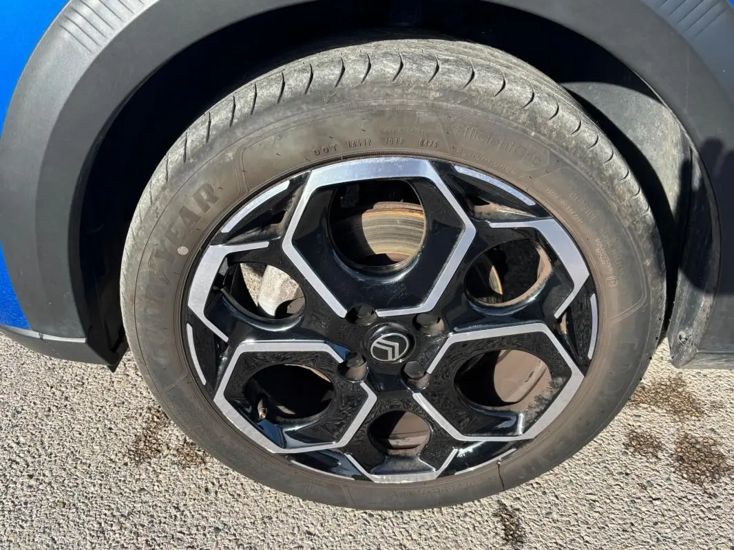 Gros plan sur la jante alliage 17 pouces noire et argentée du côté avant gauche d'une Citroën C3 bleu 2025.