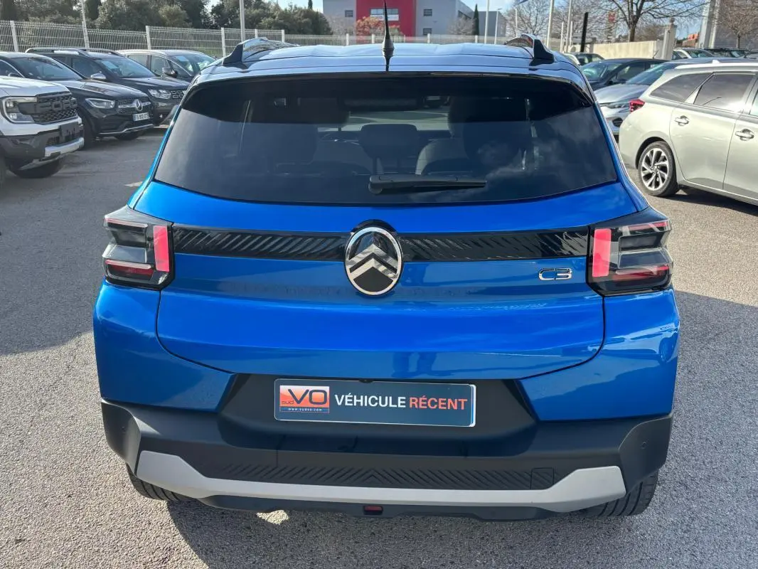 Vue arrière d'une Citroën C3 bleu vif 2025 avec barres de toit et feux arrière distinctifs en forme de "C".