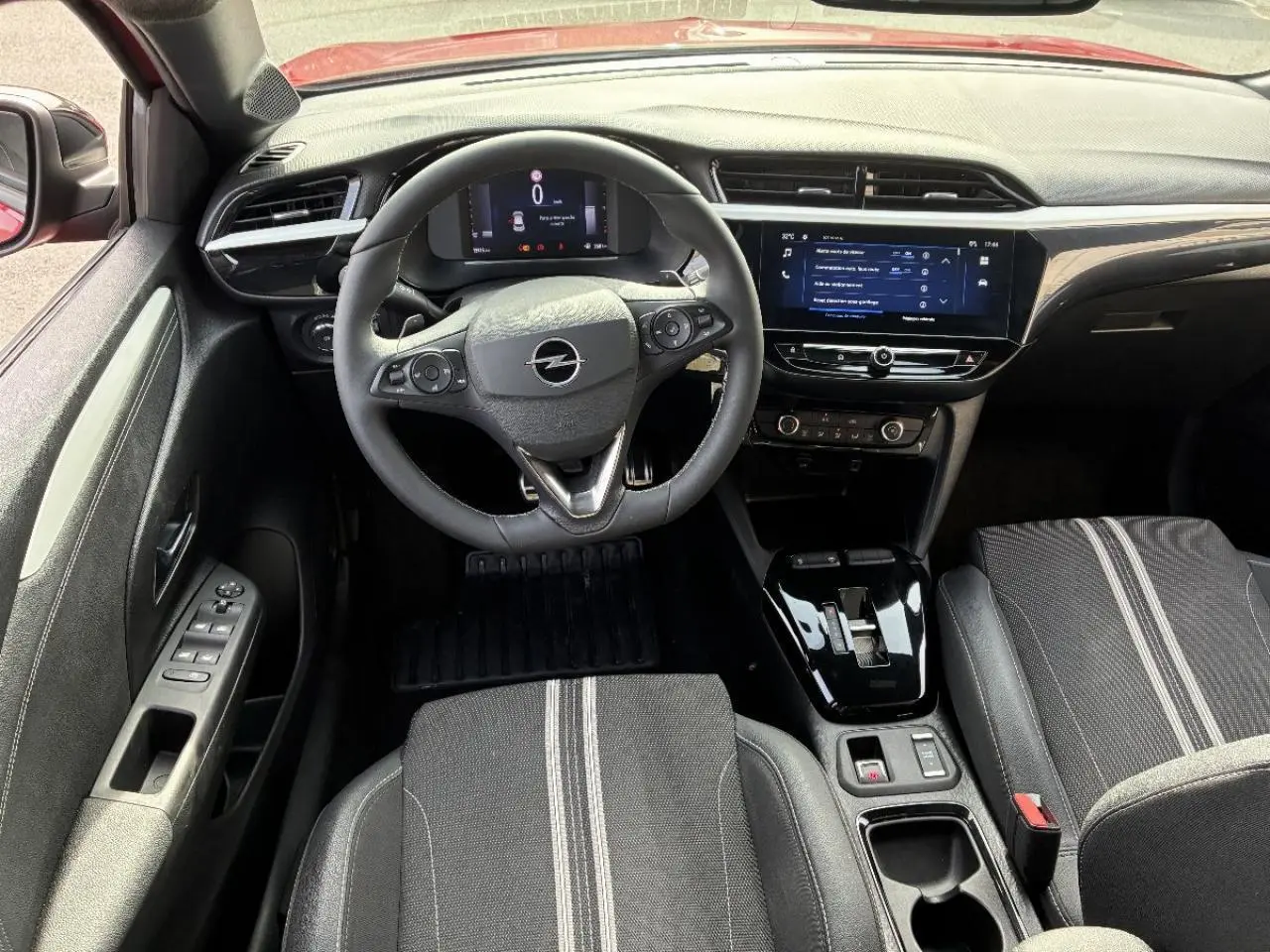 Vue intérieure avant de l’Opel Corsa 2025, volant multifonction, tableau de bord numérique et sellerie noire avec bandes grises.