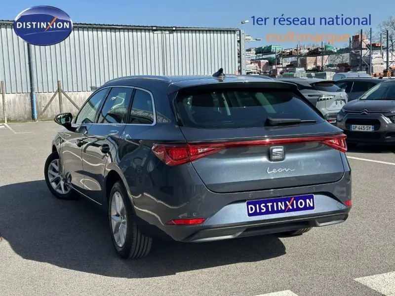 Vue 3/4 arrière droite d'une SEAT LEON ST 2025 gris magnétique métallisé avec feux arrière reliés par une bande lumineuse.