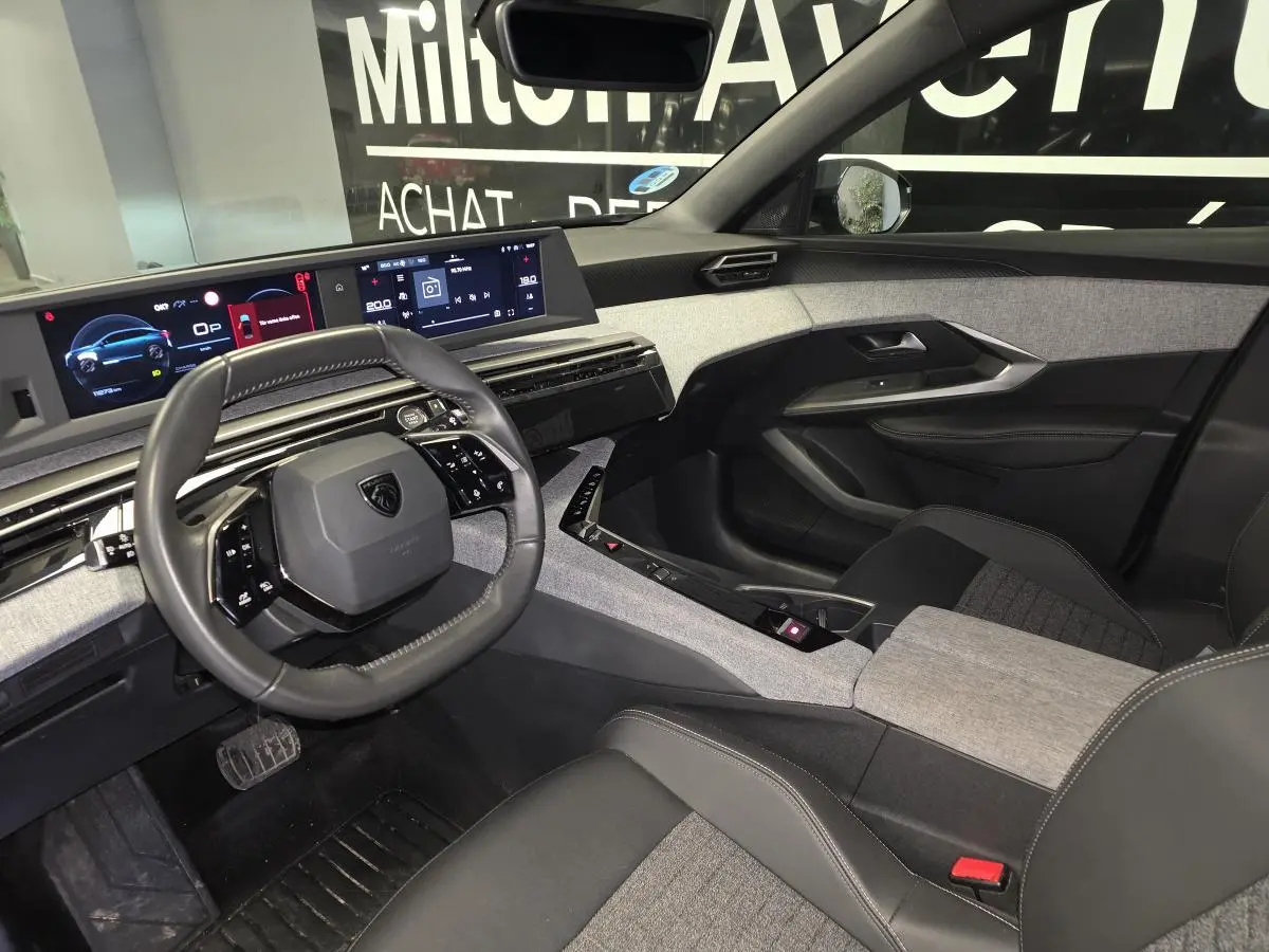 Vue intérieure côté conducteur du Peugeot 3008 2025, tableau de bord numérique et sellerie tissu gris et noir.
