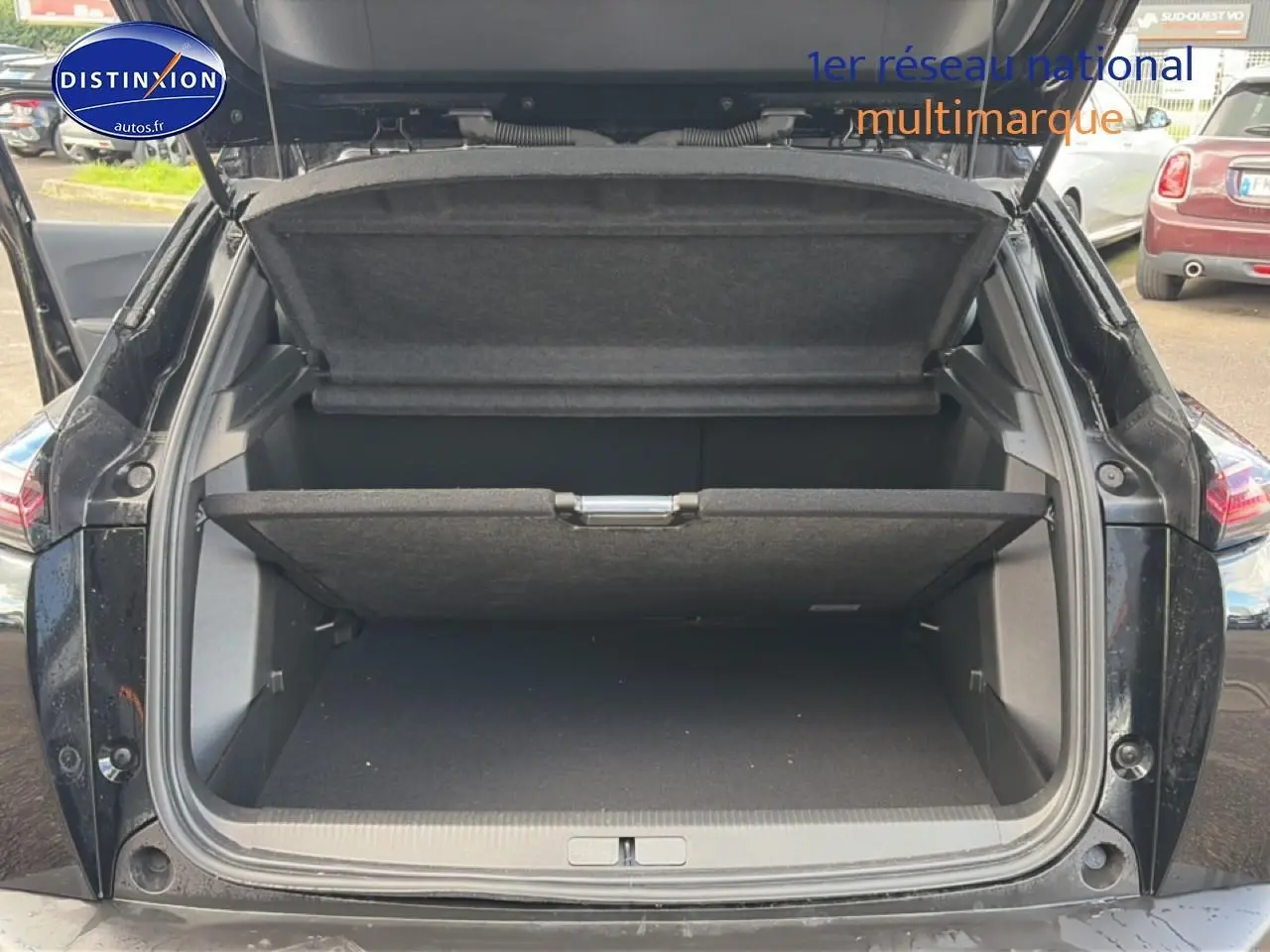 Coffre ouvert en vue arrière d’un Peugeot 2008 noir 2025 avec cache-bagages et hayon relevé.