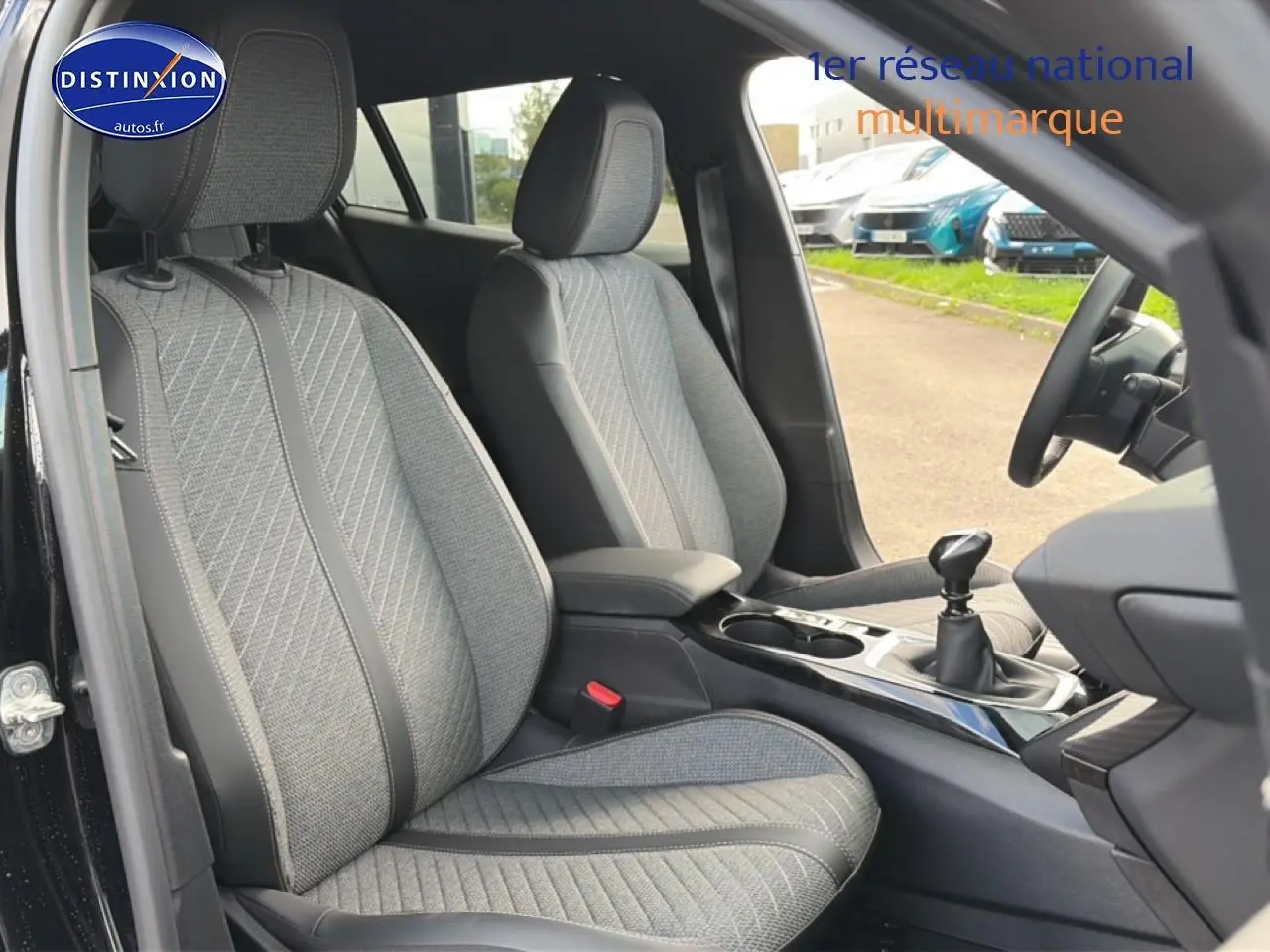 Vue intérieure côté conducteur du Peugeot 2008 noir 2025, mettant en valeur les sièges tissu gris et la boîte manuelle.