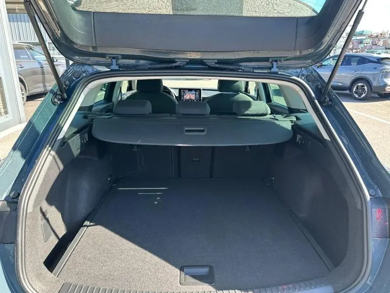 Coffre ouvert vu de l'arrière d'une SEAT LEON ST 2.0 TDI 115ch STYLE XL bleu saphir métallisé, montrant l'espace de chargement.