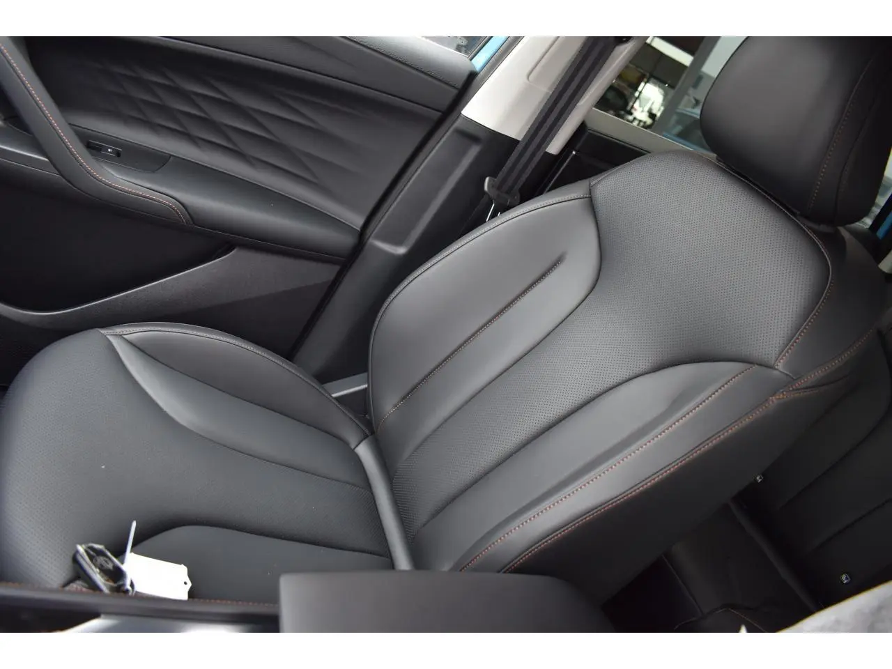 Gros plan sur le siège conducteur en similicuir noir avec surpiqûres marron du MG Motor EHS 1.5 Hybrid+ 224 ch Luxury.