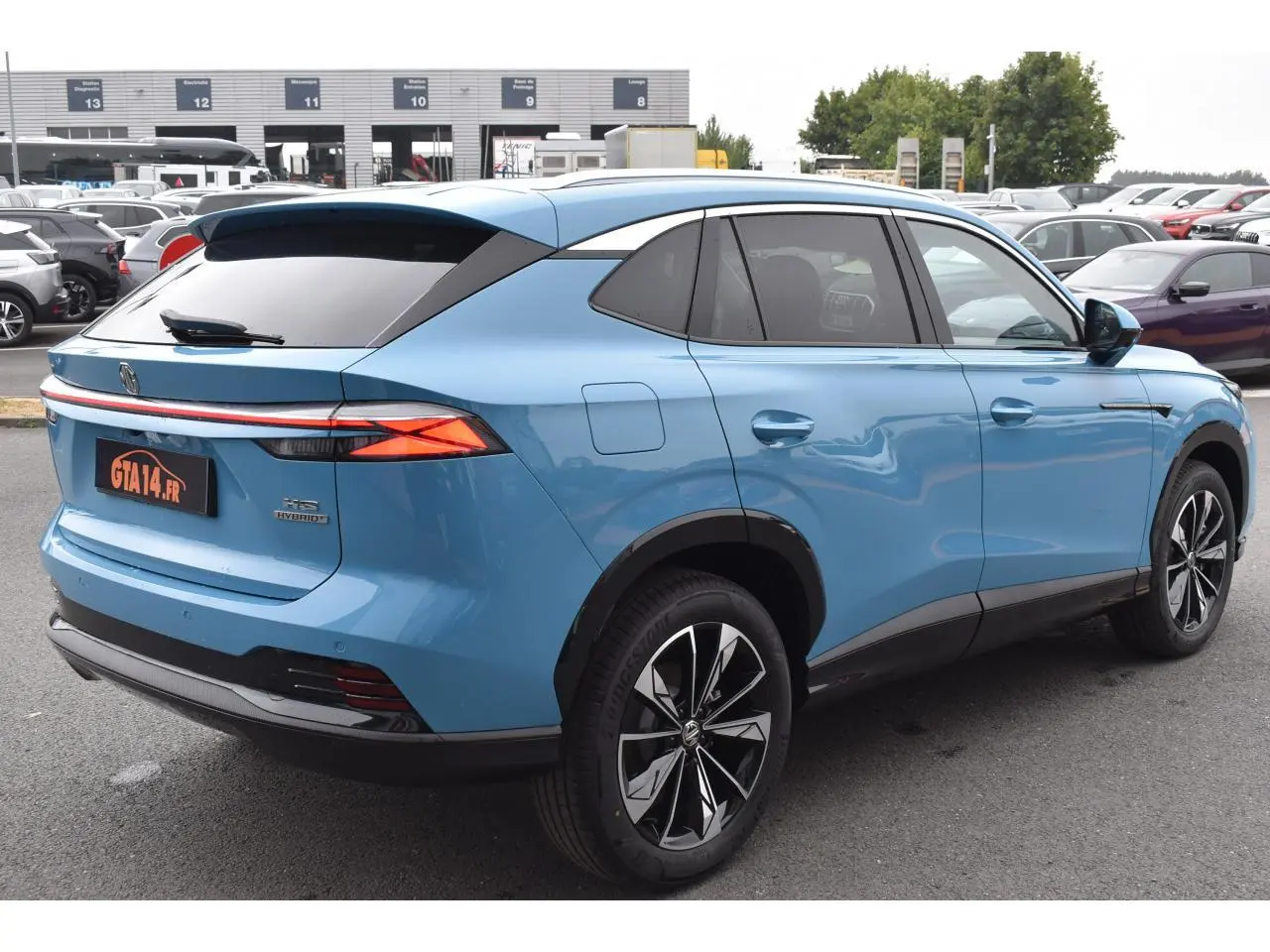 Vue 3/4 arrière droite du MG Motor EHS 1.5 Hybrid+ bleu métallisé avec jantes alliage 19 pouces et vitres surteintées.