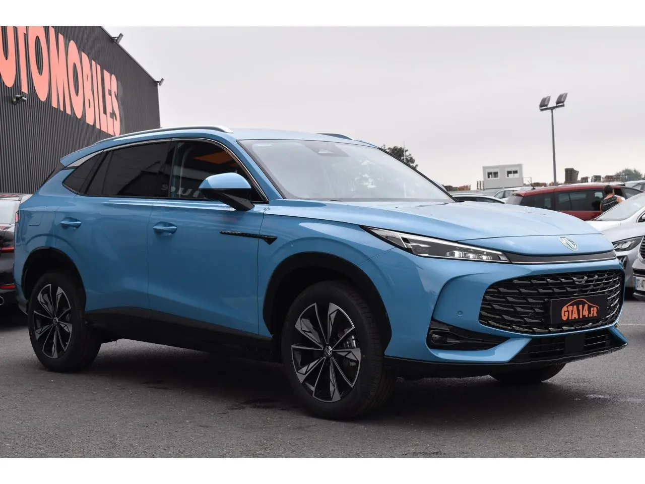 MG EHS 1.5 Hybrid+ bleu métallisé en 3/4 avant droit avec jantes alliage et calandre noire distinctive.