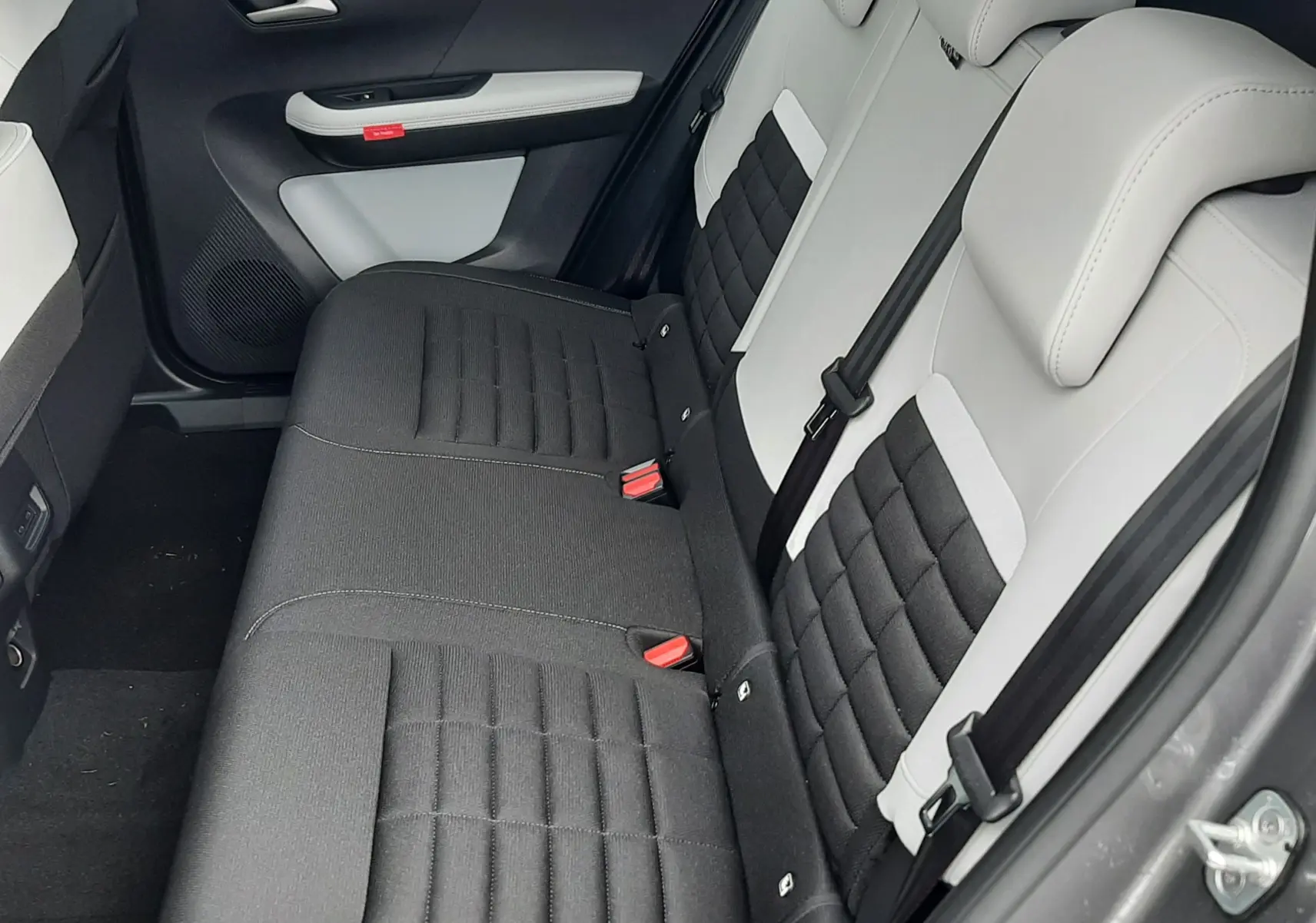Vue intérieure côté arrière droit du Citroën C3 Aircross 2026, sièges bicolores noir et blanc avec tissu matelassé.