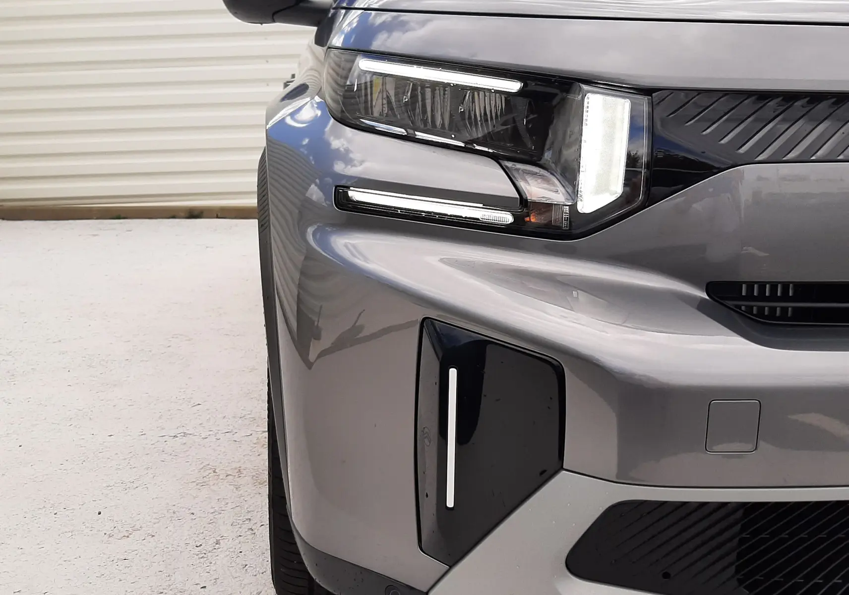 Gros plan sur l'avant gauche du Citroën C3 Aircross gris Mercury avec toit noir, mettant en valeur ses phares LED distinctifs.