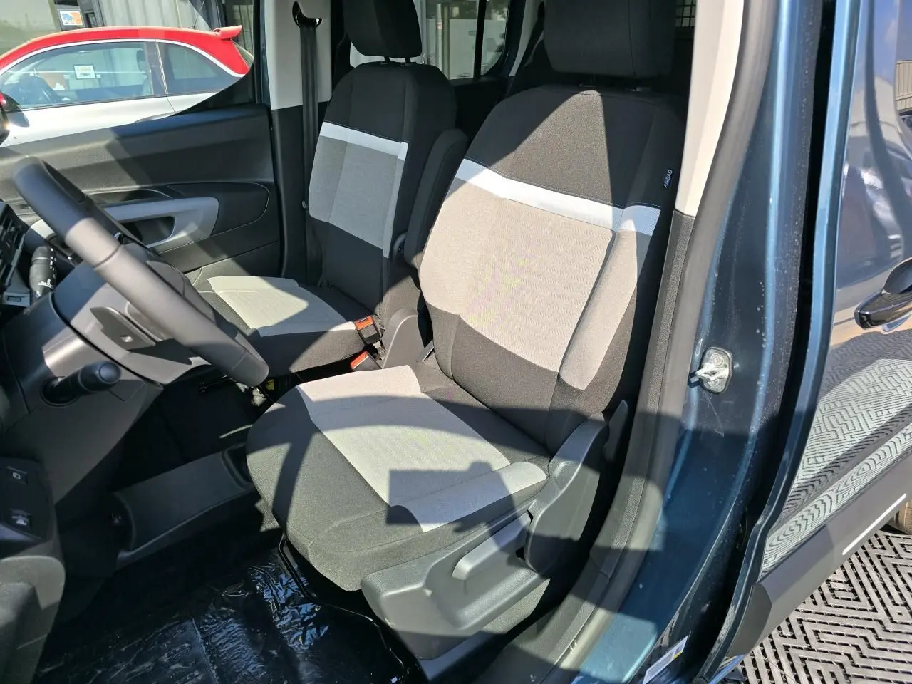 Intérieur du Citroën Berlingo bleu Kiama, vue côté conducteur sur les sièges avant en tissu bicolore.