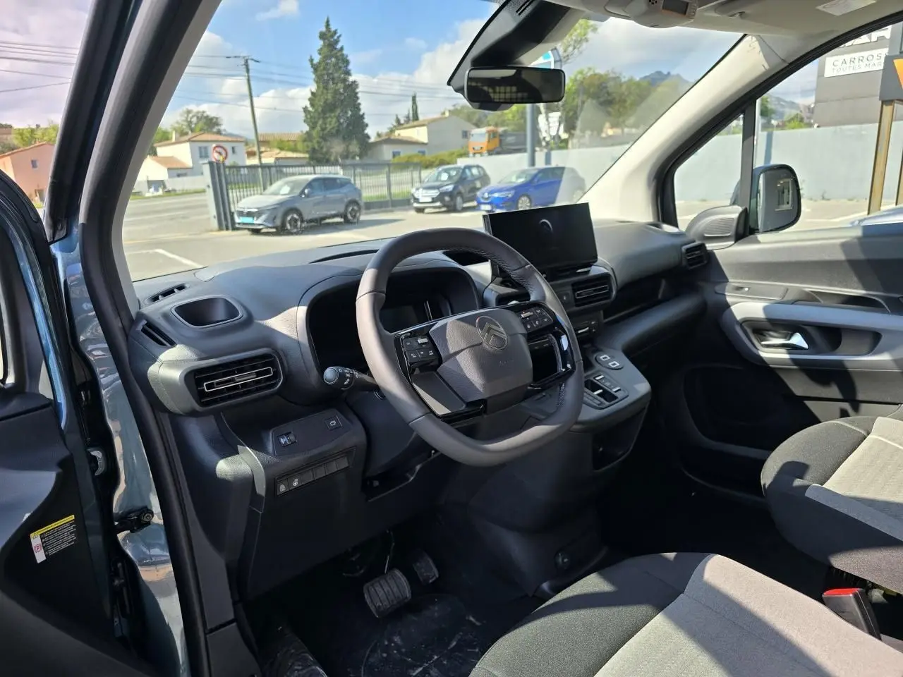Intérieur avant du Citroën Berlingo bleu Kiama, volant cuir multifonction et tableau de bord moderne avec écran tactile.