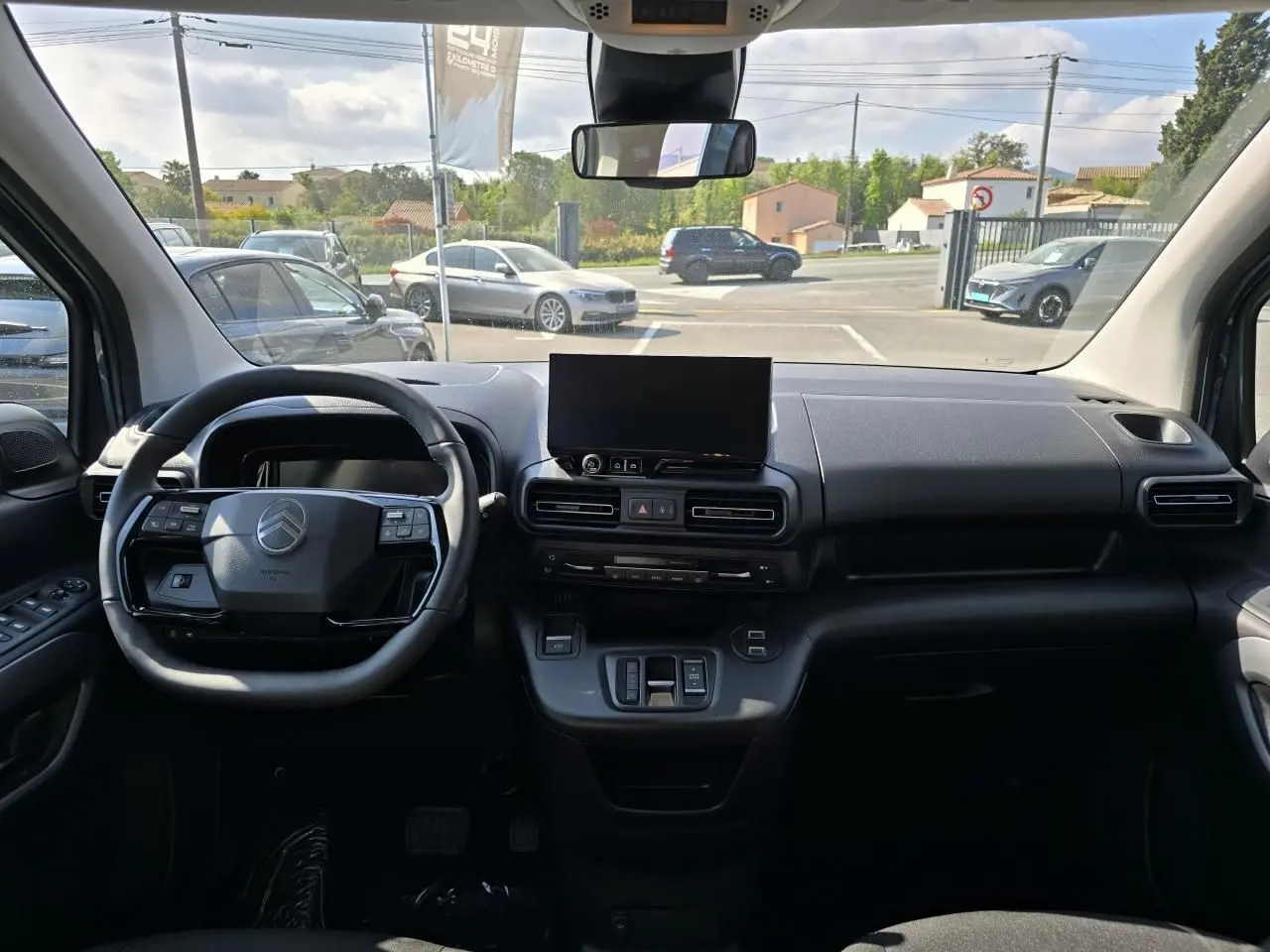 Vue intérieure du tableau de bord du Citroën Berlingo bleu Kiama, avec volant multifonction et écran tactile central.