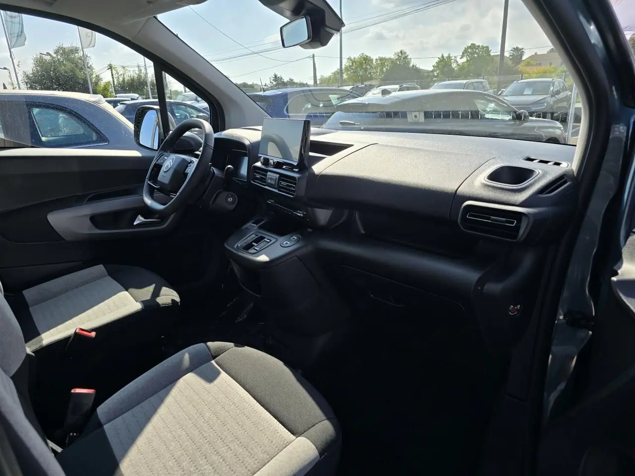 Intérieur avant du Citroën Berlingo bleu Kiama, vue côté conducteur montrant tableau de bord et sièges gris bicolores.