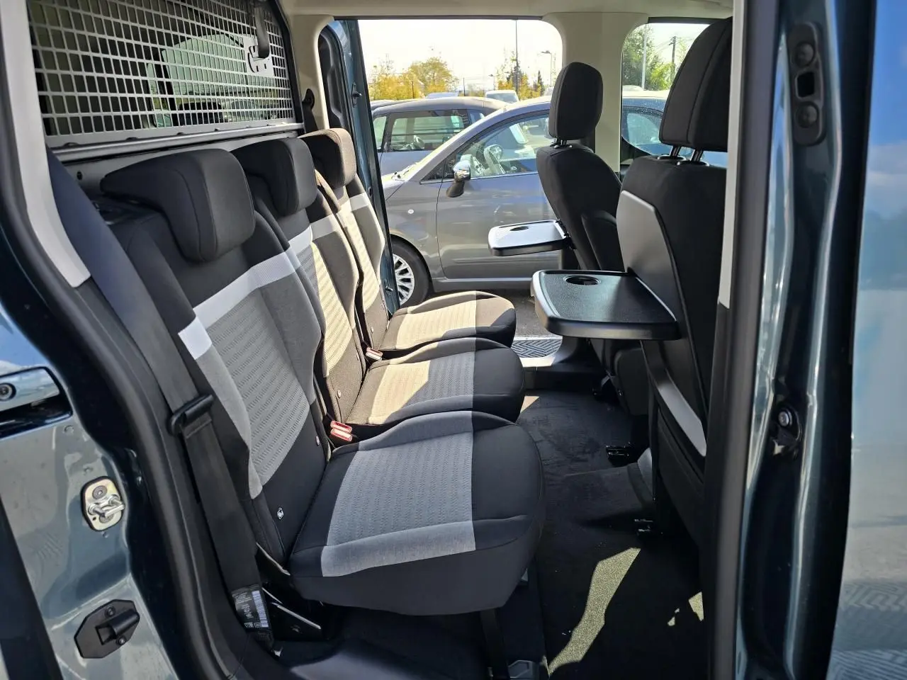 Intérieur arrière du Citroën Berlingo bleu Kiama, vue côté gauche sur les trois sièges individuels avec tablette rabattable.