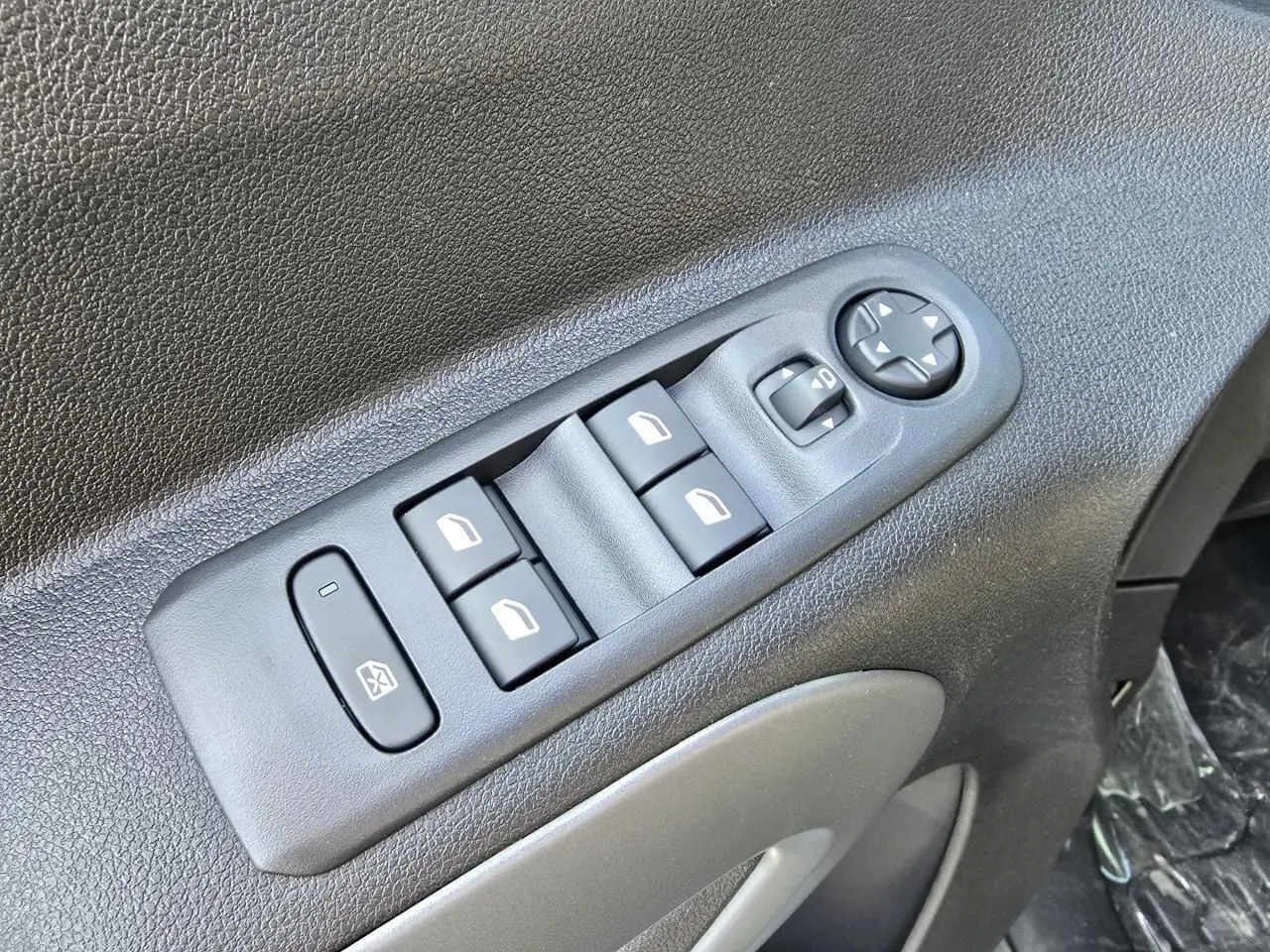 Gros plan sur les commandes des lève-vitres et rétroviseurs électriques côté conducteur du Citroën Berlingo bleu Kiama métal.