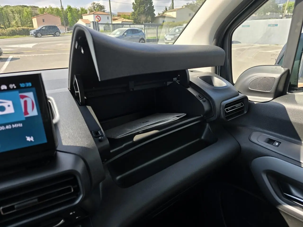 Vue intérieure côté passager du Citroën Berlingo 2025 bleu Kiama, boîte à gants ouverte et tableau de bord noir.