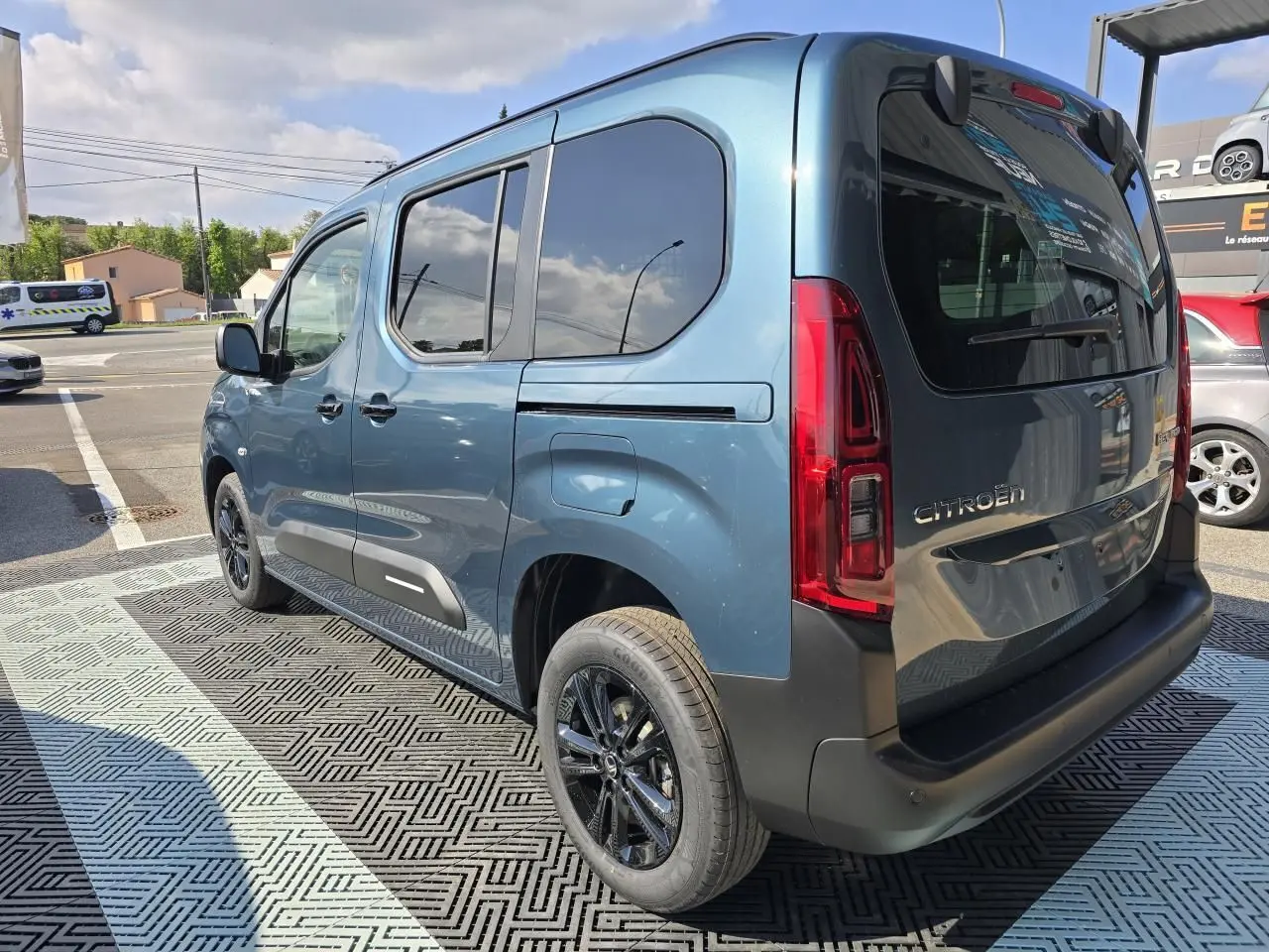 Vue 3/4 arrière droite du Citroën Berlingo bleu Kiama métallisé avec vitres arrière teintées et jantes aluminium noires.