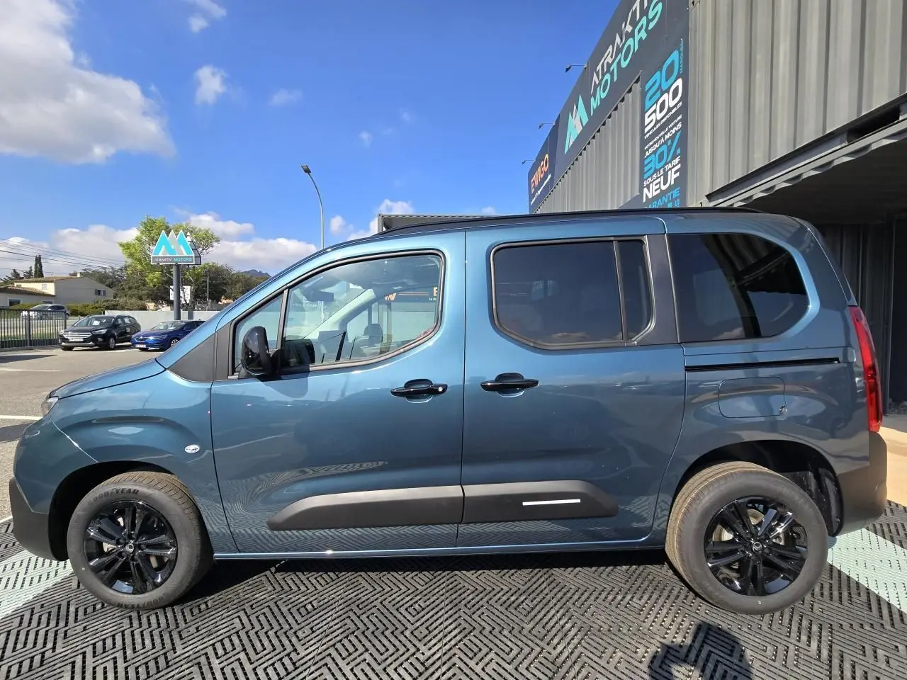 Profil droit du Citroën Berlingo bleu Kiama métallisé avec vitres arrière teintées et jantes aluminium noires.