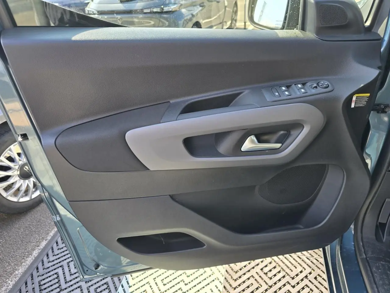 Vue rapprochée de la porte avant gauche bleu Kiama métallisé du Citroën Berlingo 2025 avec commandes de vitres et poignée grise.