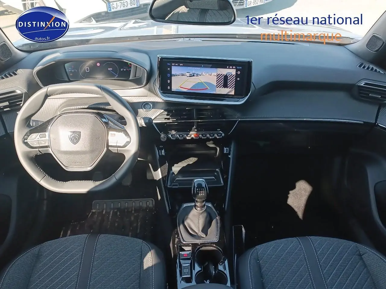 Vue intérieure avant de la Peugeot 2008 gris artense 2025, volant multifonction et écran tactile avec caméra de recul.