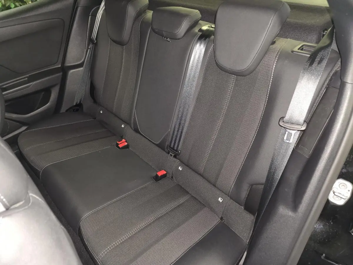 Vue intérieure de la banquette arrière noire de l'Opel Mokka-e 2025 avec ceintures et appuie-têtes visibles.