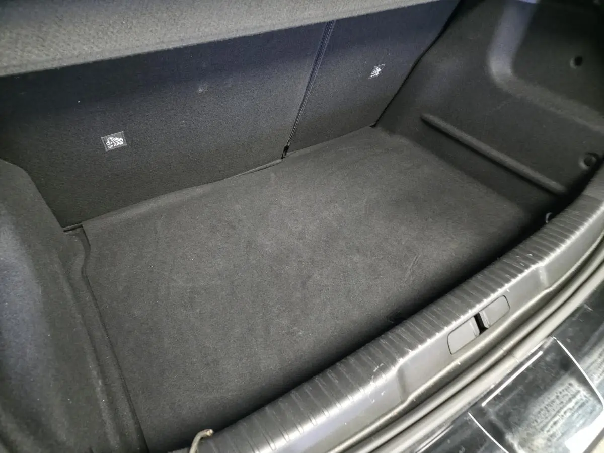 Coffre vide en vue plongeante d'un Opel Mokka-e noir, montrant la moquette noire et les fixations Isofix arrière.