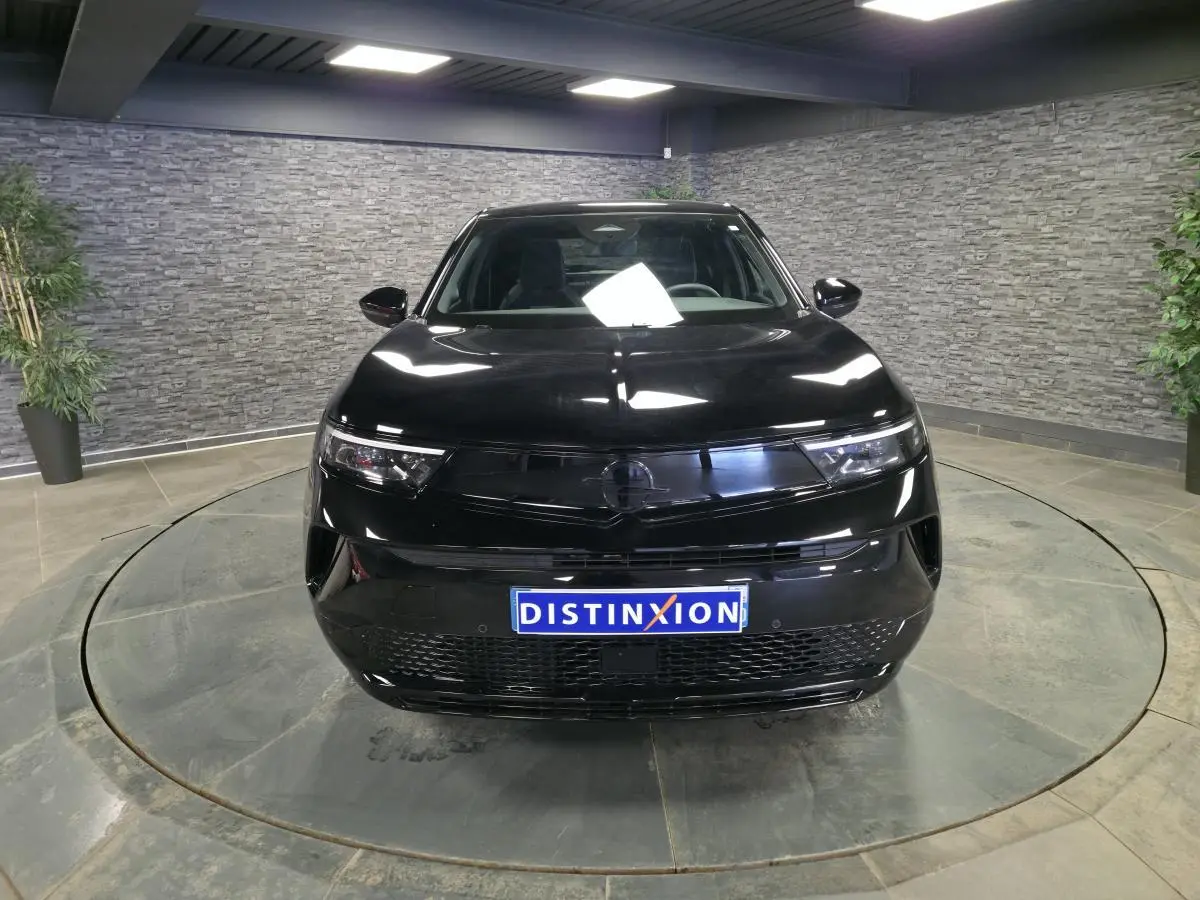 Vue avant d'un Opel Mokka-e noir 2025 avec calandre noire et phares Matrix LED dans un showroom.