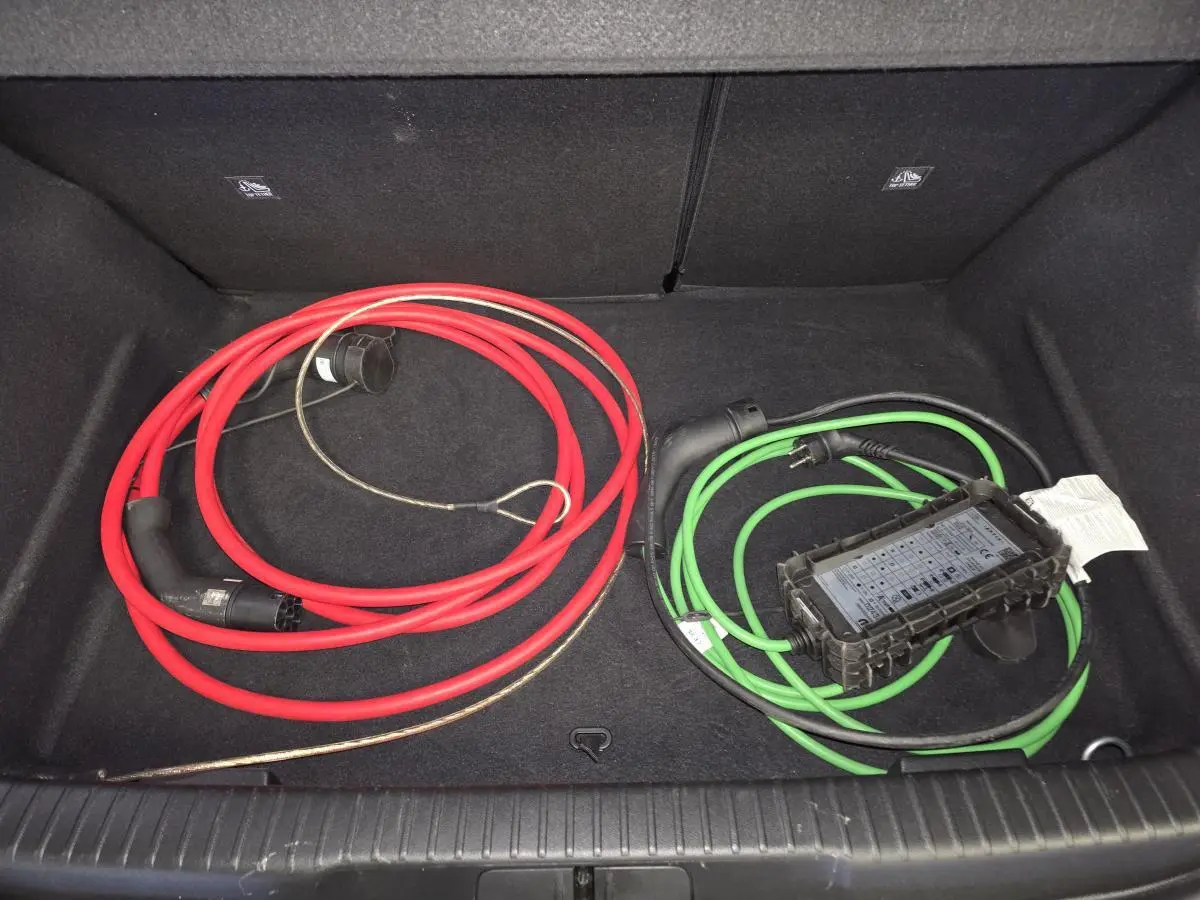 Coffre ouvert d’Opel Mokka-e noir, vue de dessus montrant câbles de recharge rouge et vert rangés.