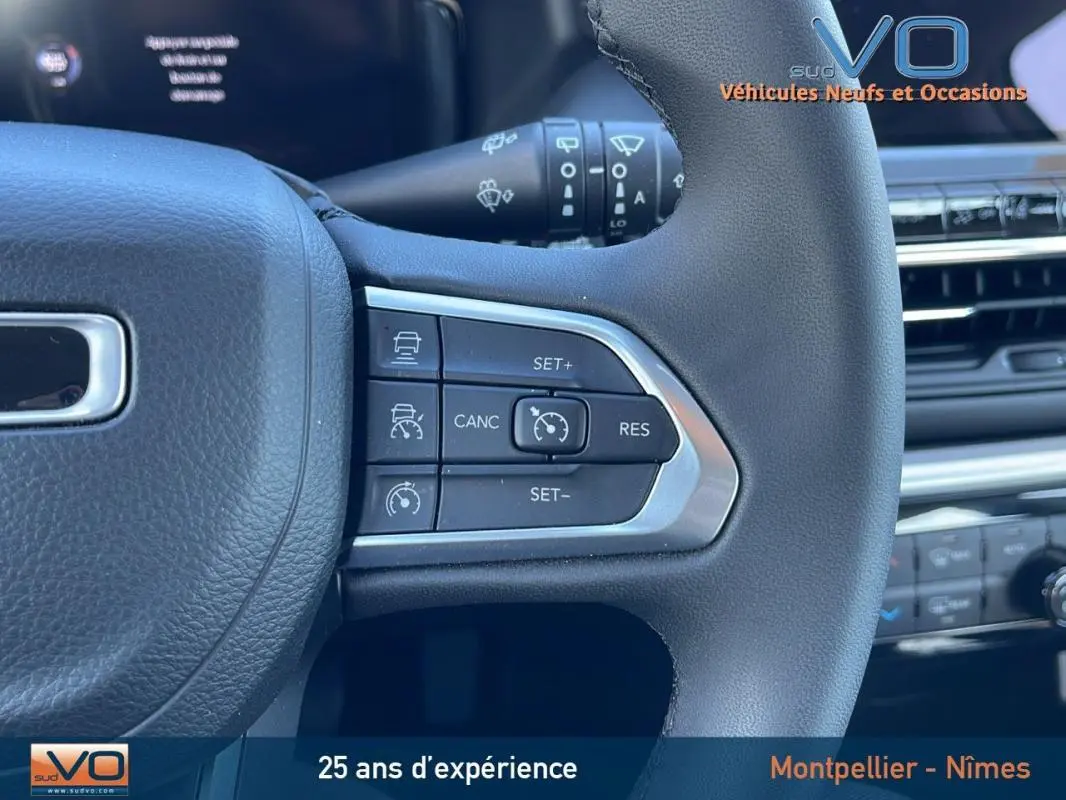 Gros plan sur les commandes du régulateur de vitesse au volant d'un Jeep Compass blanc 2024, intérieur moderne.